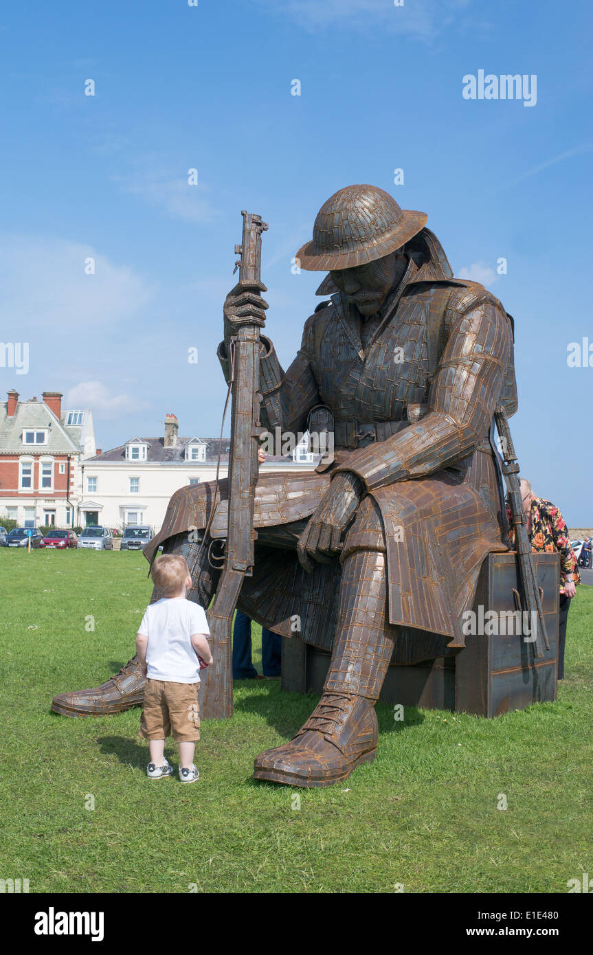 Un giovane bambino guardando Tommy un acciaio corten scultura di WW1 soldato da Ray Lonsdale, Seaham Harbour North East England, Regno Unito Foto Stock