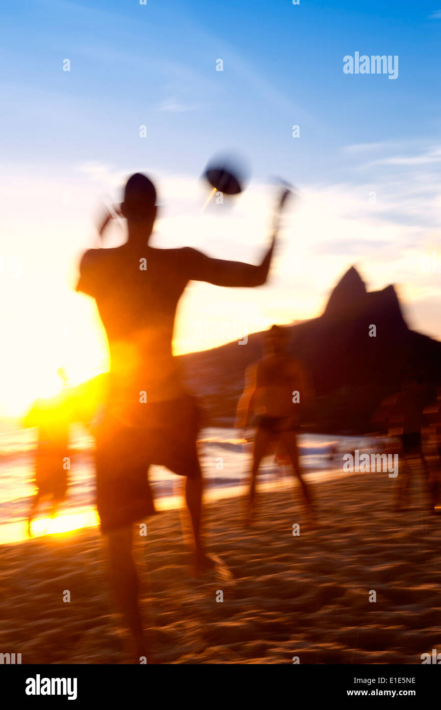 Sagome di brasiliani giocando keepy uppy altinho futebol beach soccer football in un tramonto blur a postero Nove Ipanema Rio Foto Stock