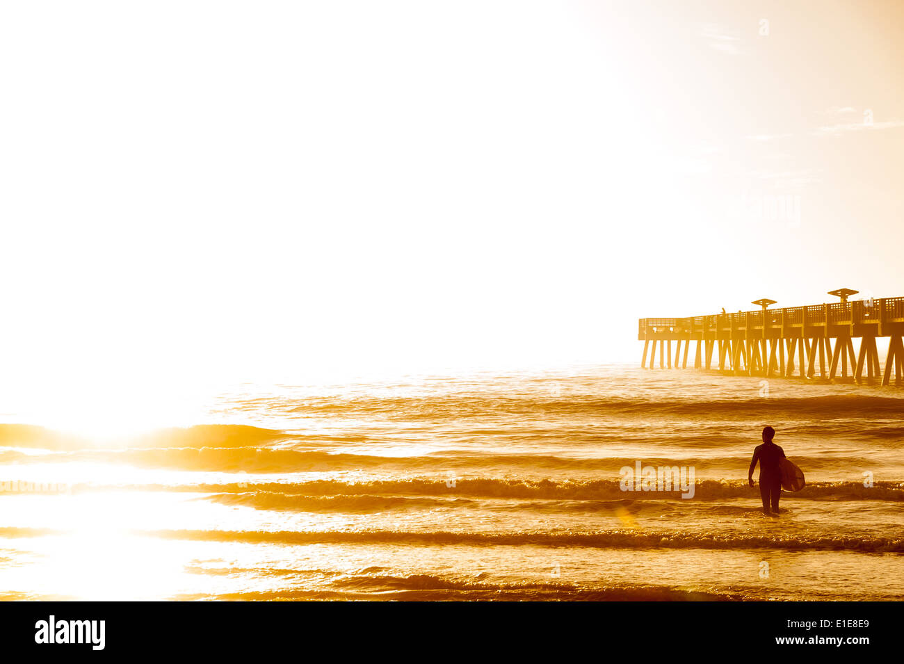 Un surfista della Florida saluta il nuovo giorno su un golden sunrise mattina a Jacksonville Beach. Stati Uniti d'America. Foto Stock