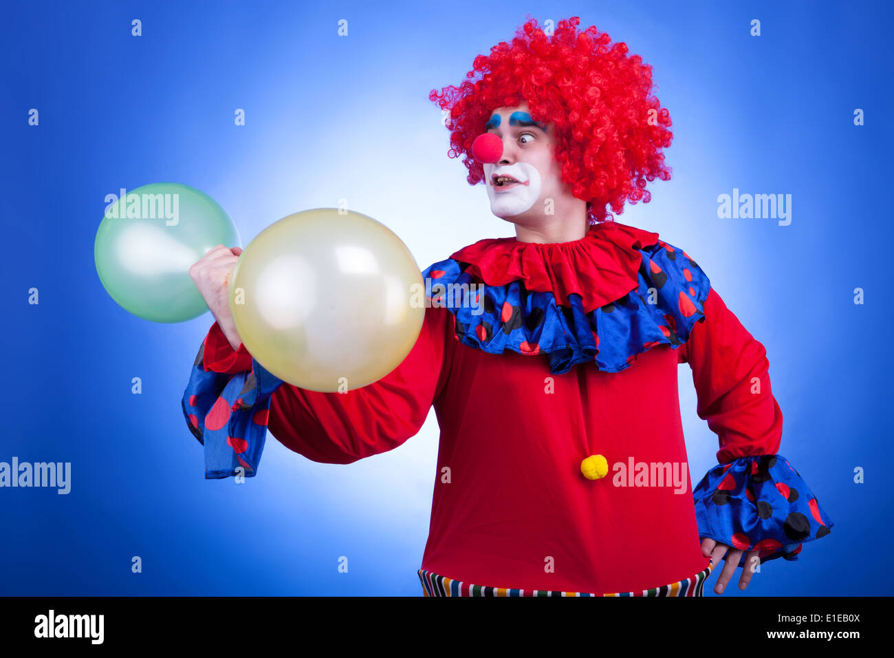 Clown con palloncini in mano su sfondo blu. Colori vividi Foto Stock