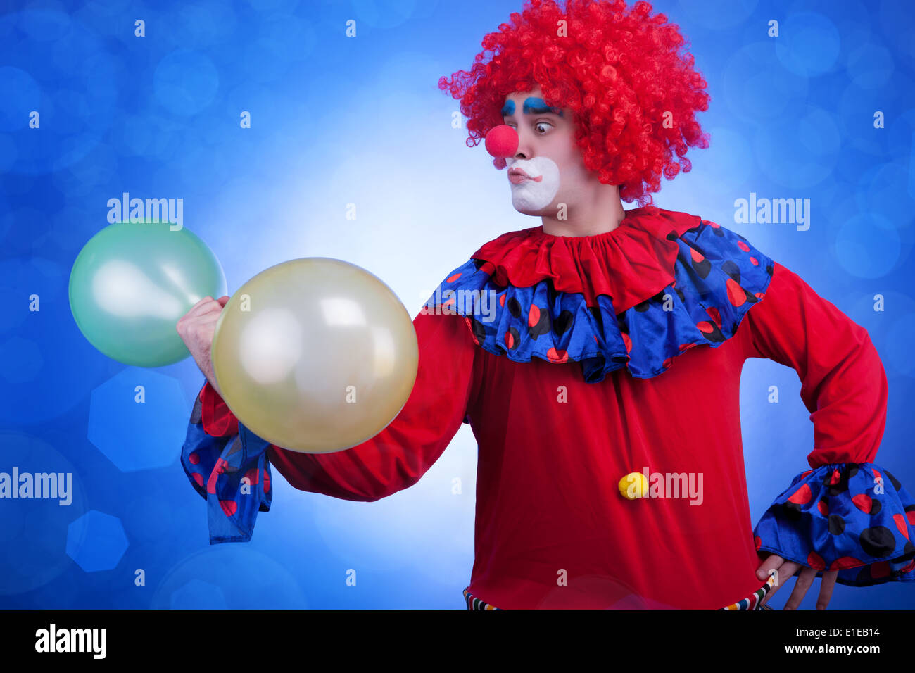 Clown con palloncini in mano su sfondo blu. Colori vividi Foto Stock