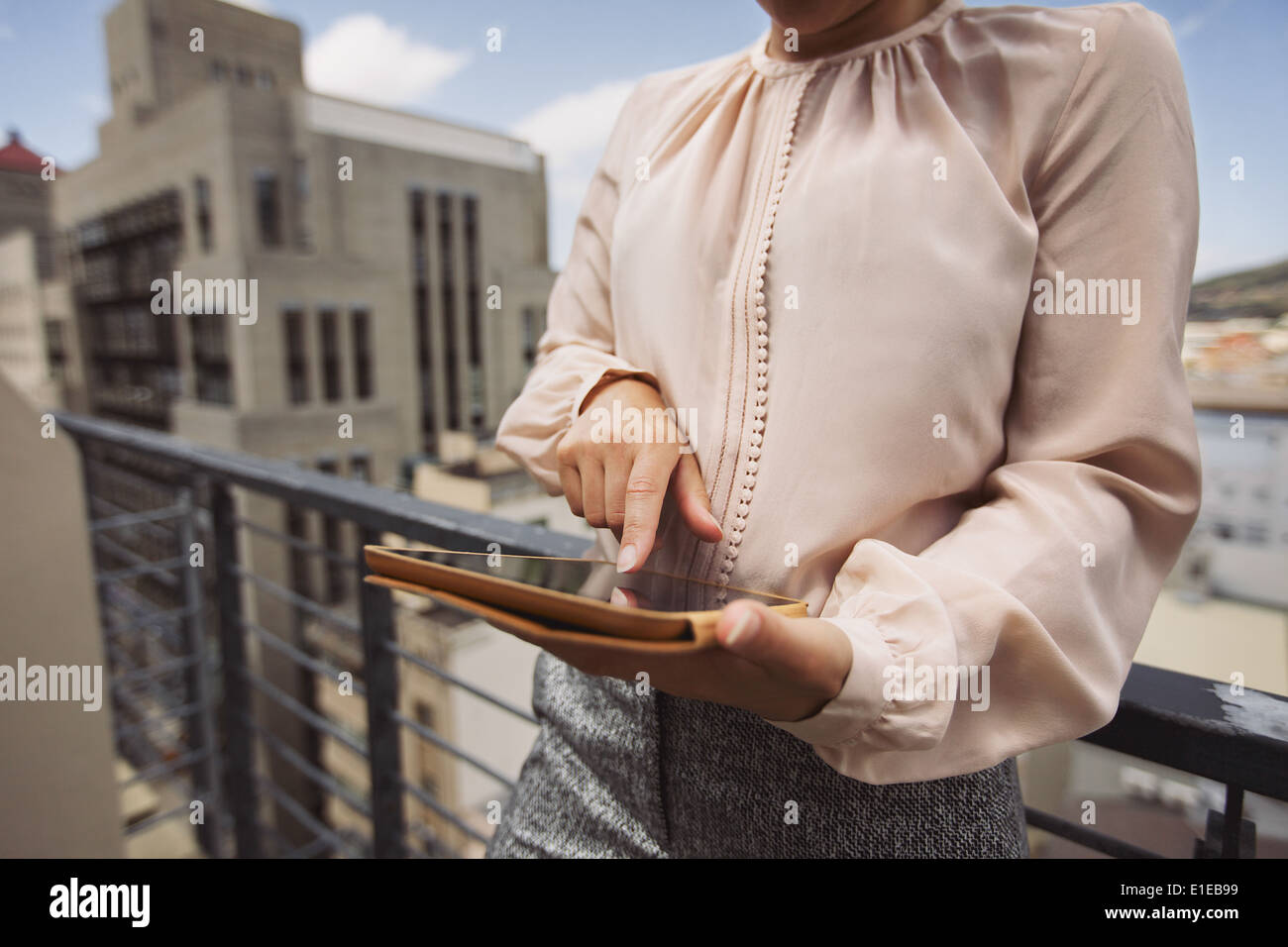 Giovane donna in piedi sul balcone utilizzando tablet PC. Immagine ritagliata del lavoro femminile sulla tavoletta digitale. Foto Stock