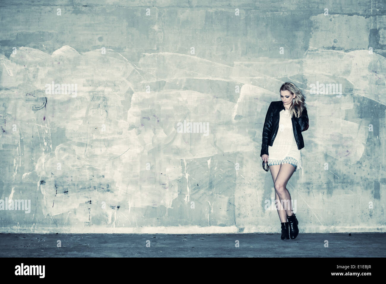 Bella ragazza urbano si appoggia contro un muro di cemento, croce immagine elaborata Foto Stock