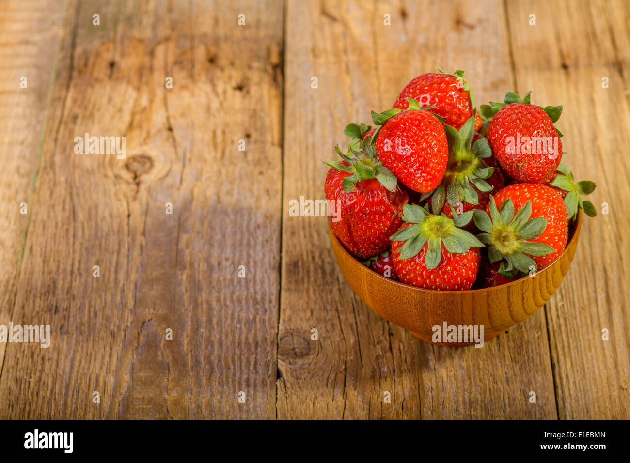 Fragole fresche nella ciotola di legno sul vecchio sfondo di legno Foto Stock