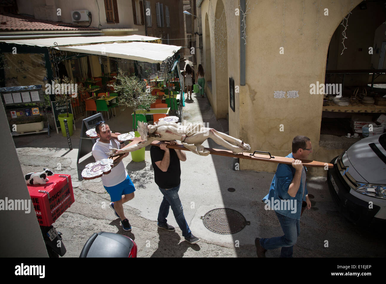 Gli uomini con la statua del Cristo sulla croce attraverso le strade della città di Calvi, in Corsica. Foto Stock