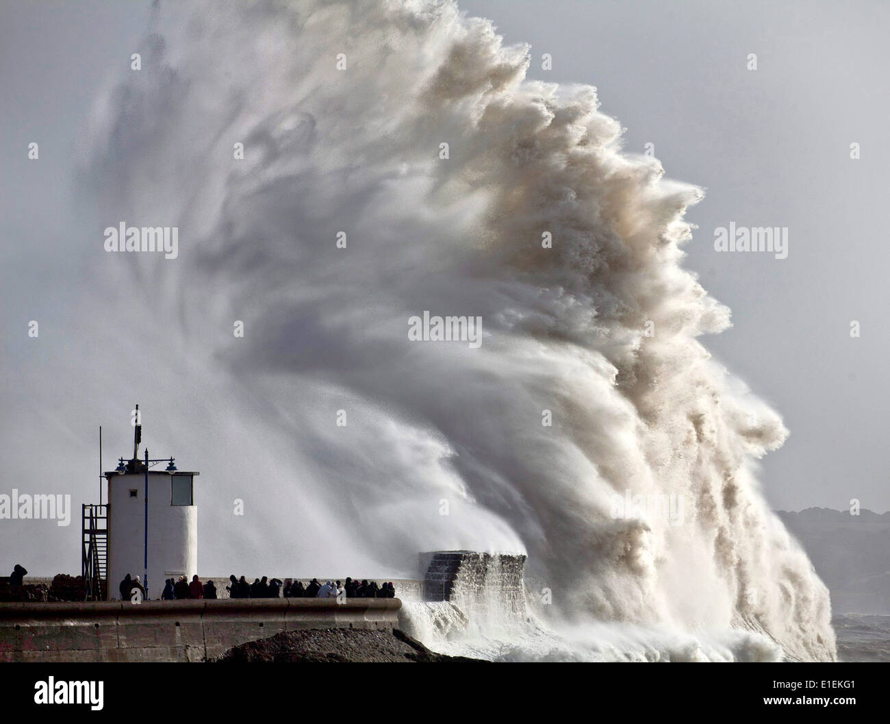 Decine di persone pack mura sul mare a Porthcawl nel Galles del Sud per guardare le massicce ondate di colpire il faro Foto Stock