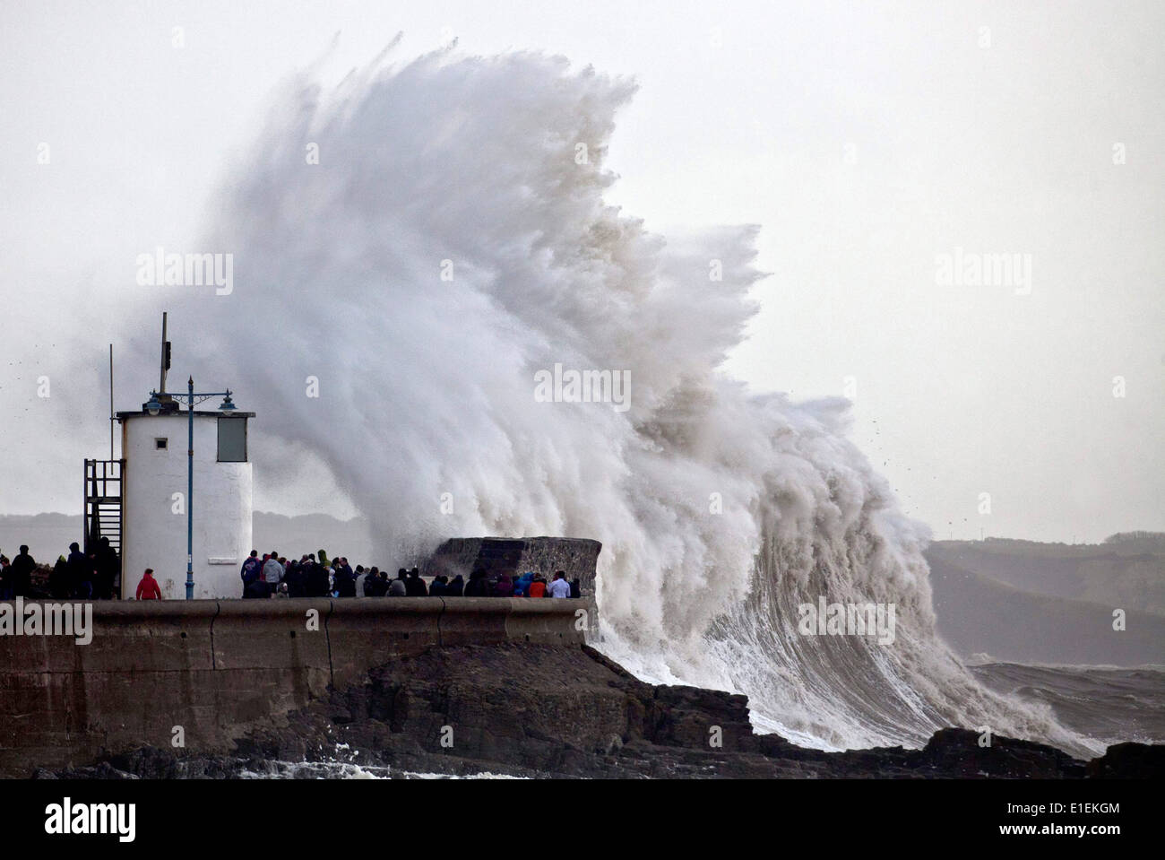 Decine di persone pack mura sul mare a Porthcawl nel Galles del Sud per guardare le massicce ondate di colpire il faro Foto Stock