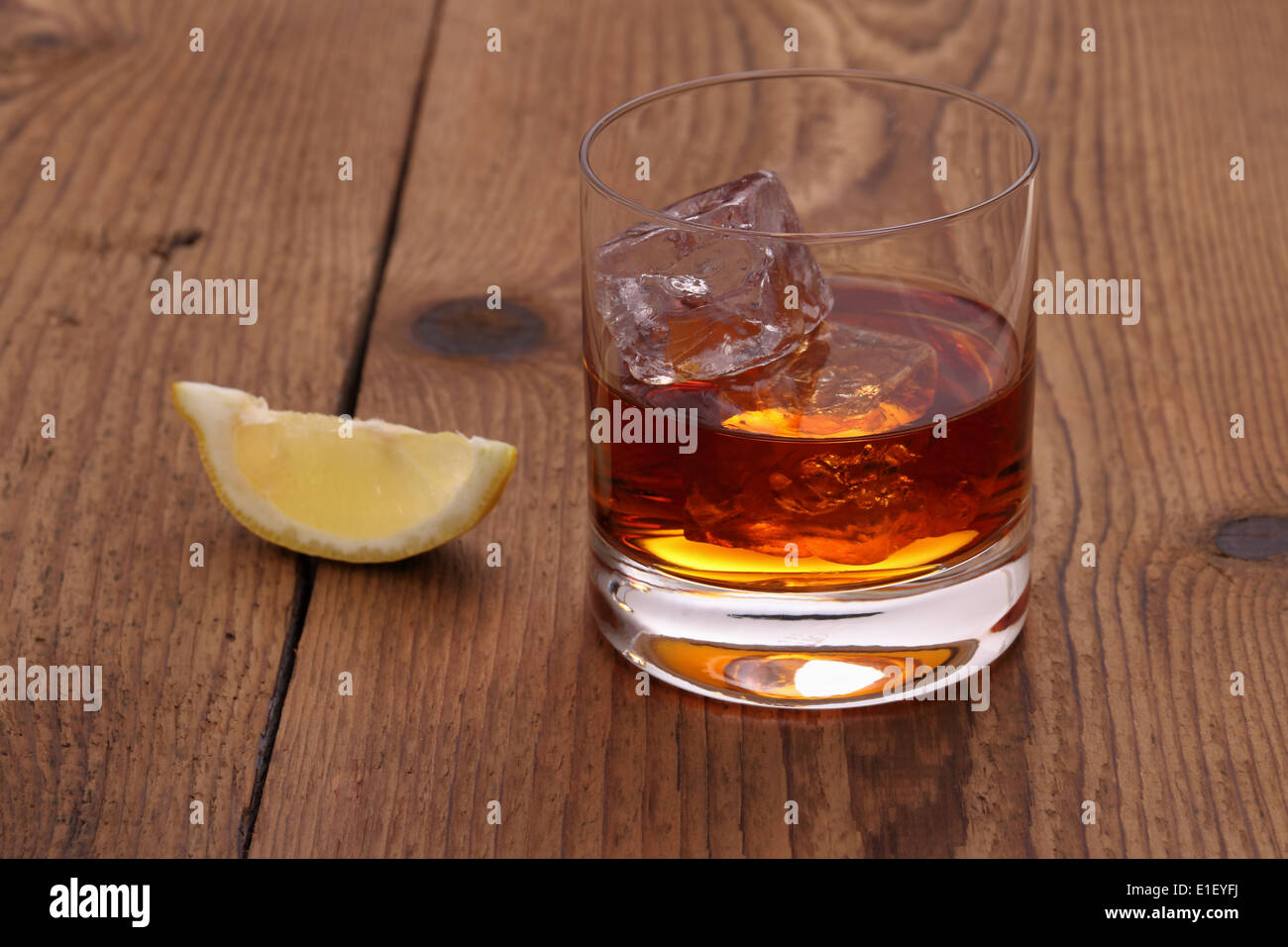 Il whiskey con cubetti di ghiaccio in vetro su uno sfondo di legno Foto Stock