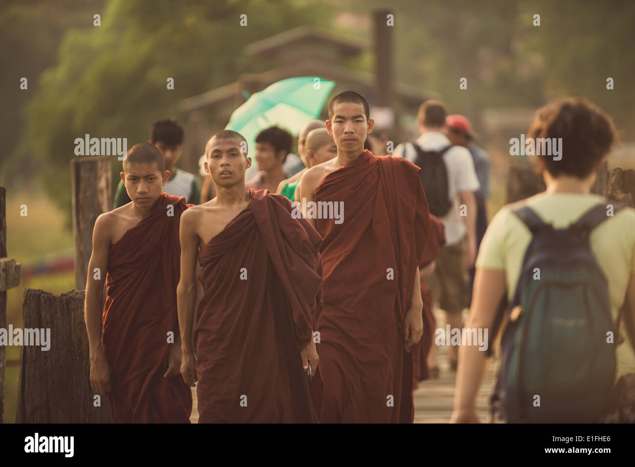 I giovani monaci buddisti a piedi passato turisti sul popolare U Bein ponte di legno in Myanmar. Foto Stock