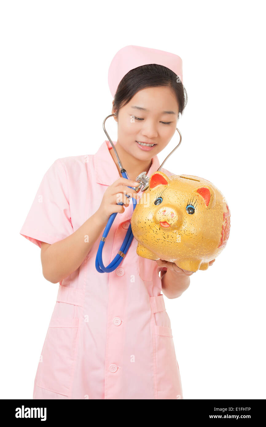 Belle infermiere cinese fingendo di ascoltare il battito cardiaco di un salvadanaio. Il costo delle cure mediche Foto Stock