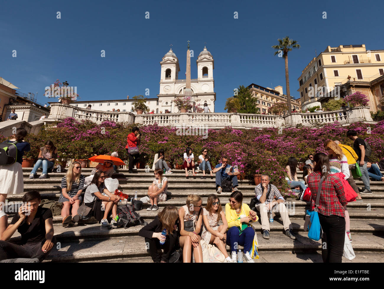 I turisti seduti sulla scalinata di Piazza di Spagna, con le Azalee in fiore in primavera; Roma Centro, Italia Europa Foto Stock