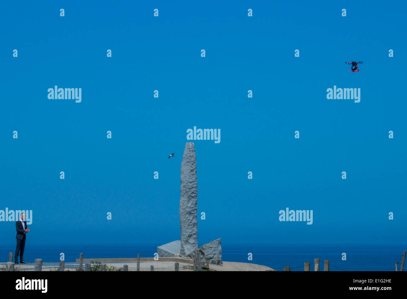 Point du Hoc, Normandia, Francia. Un newsman francese è fotografato con la fotocamera di un drone vicino al memoriale di Ranger. Un gabbiano vola da. Foto Stock
