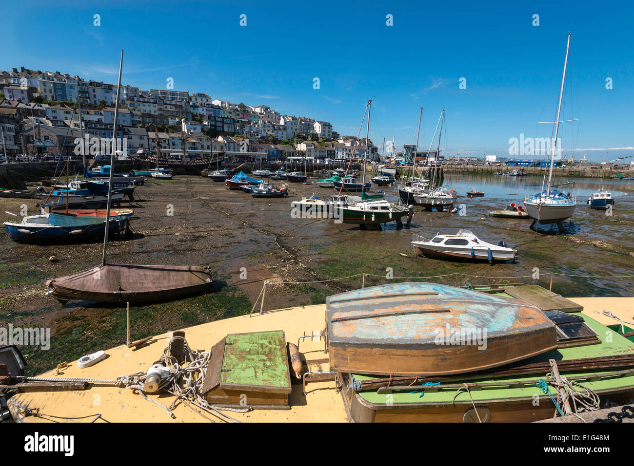 BRIXHAM Harbour nel Devon a bassa marea con barche e yacht ormeggiati . Barca con dinghy sul ponte in primo piano.Case in background Foto Stock