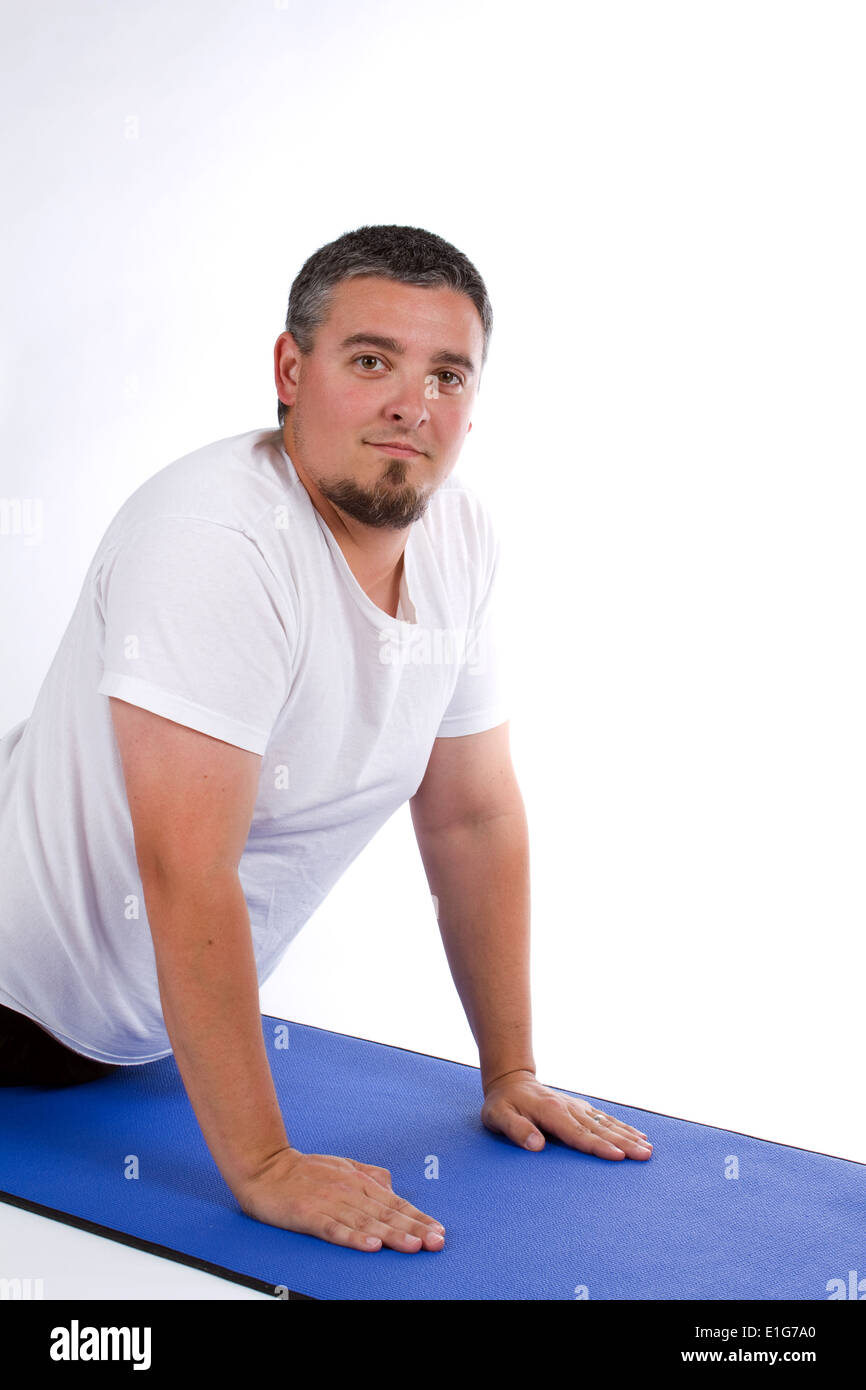 Il sovrappeso maschio adulto si allunga in un yoga pone su un tappetino. Foto Stock