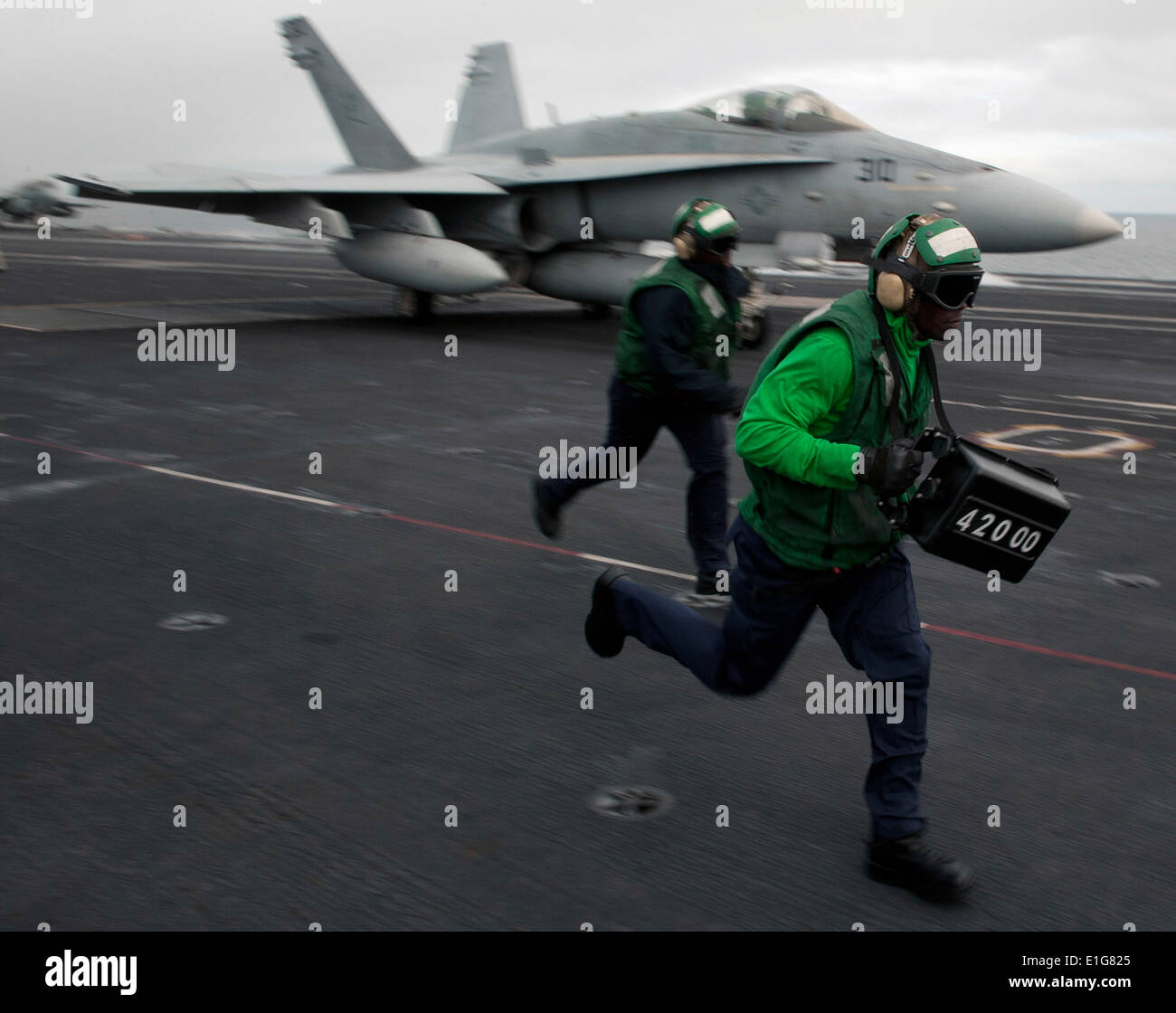 Stati Uniti Aviazione Navale di Boatswain Mate Airman Terrance Chase, destro corre con un peso da un F/A-18C Hornet aeromobile come lui e Foto Stock