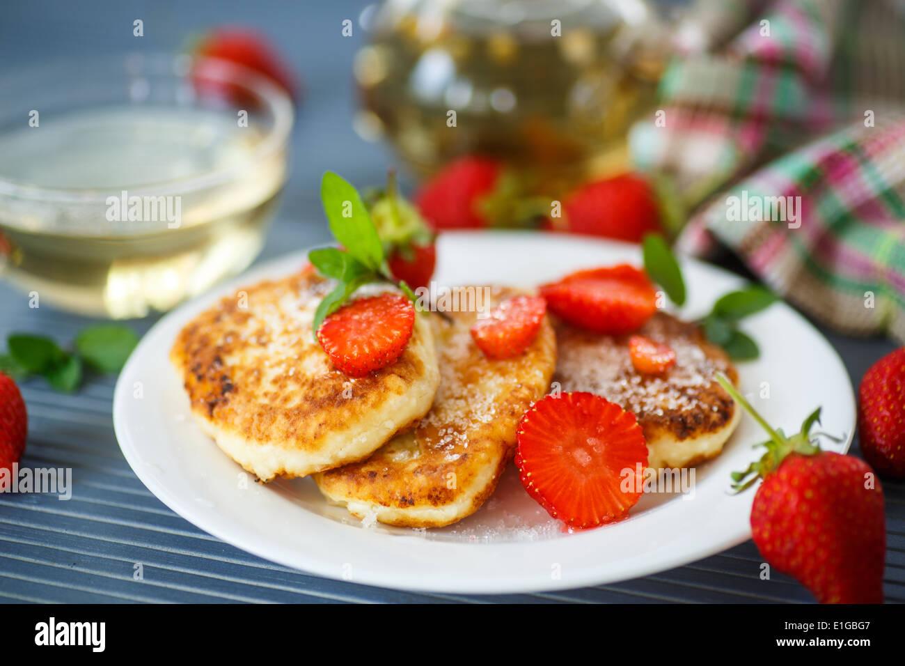 Ricotta frittelle fritte con lo zucchero e le fragole su una piastra Foto Stock