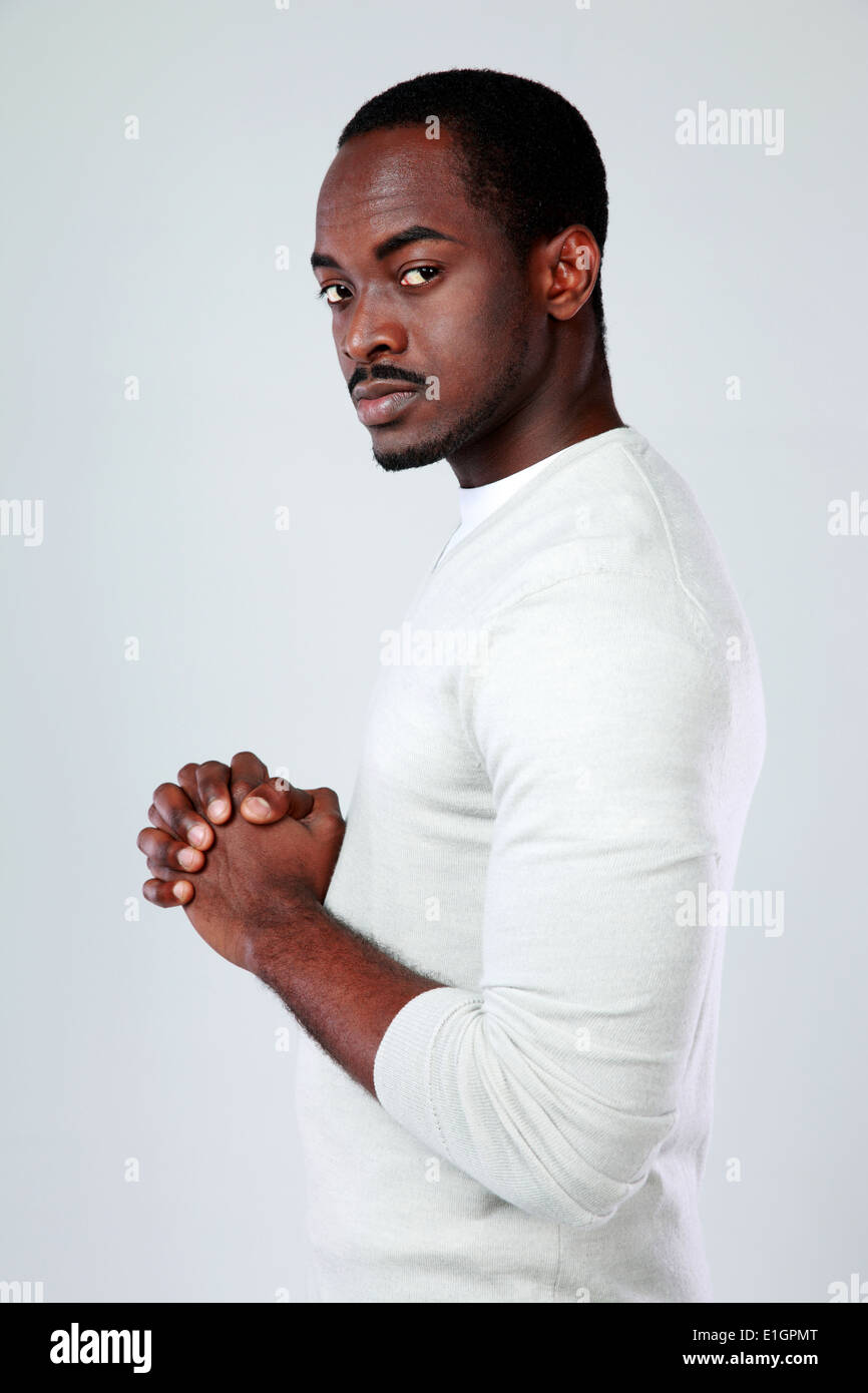 Vista laterale verticale di una grave uomo africano su sfondo grigio Foto Stock