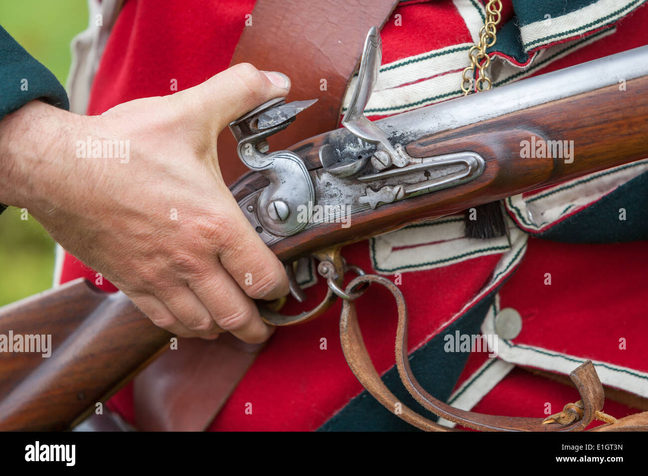 Un soldato vestito in tradizionali del XVII secolo Esercito Inglese Redcoat caricamento uniforme un moschetto flintlock. Foto Stock