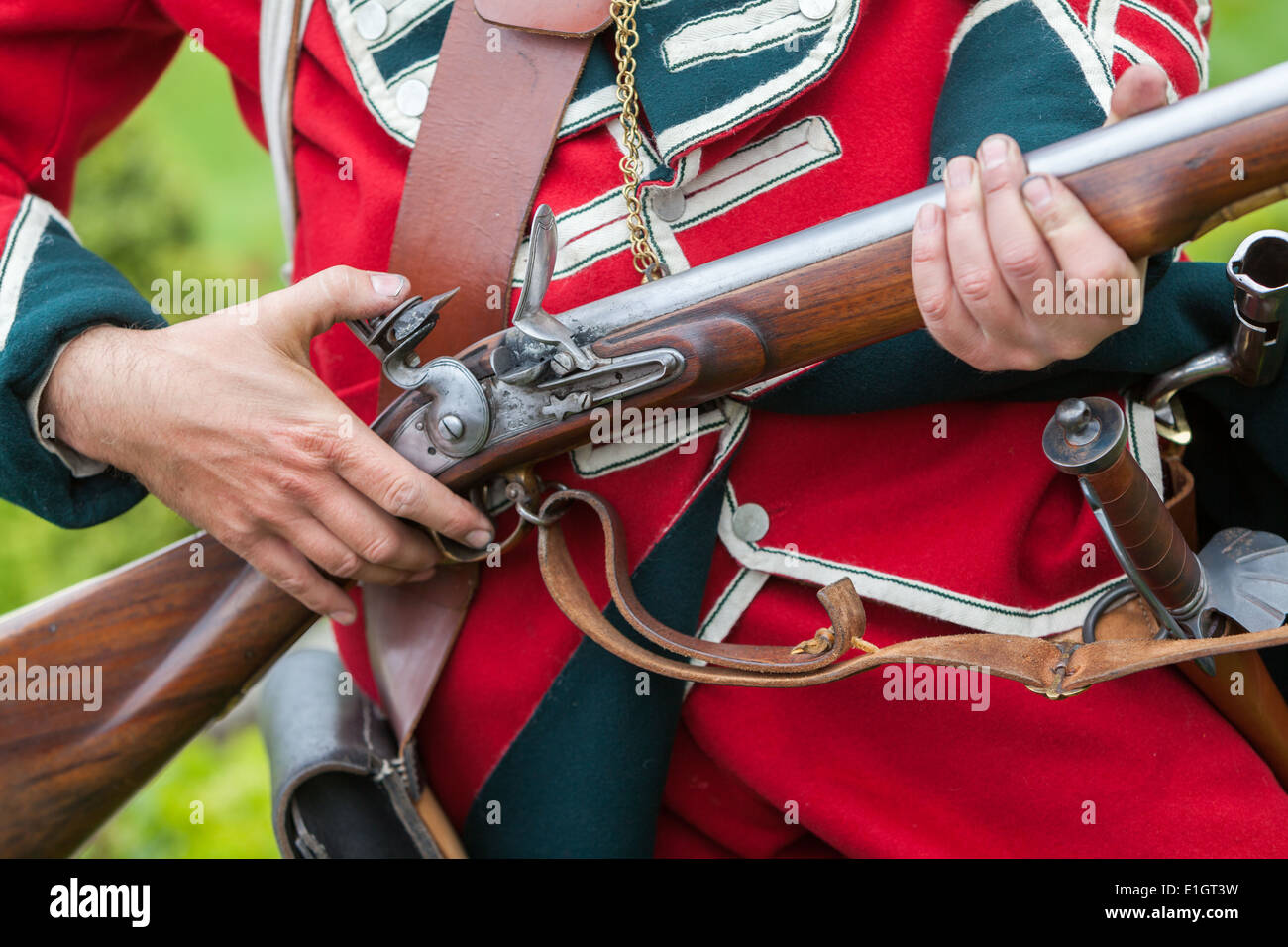 Un soldato vestito in tradizionali del XVII secolo Esercito Inglese Redcoat caricamento uniforme un moschetto flintlock. Foto Stock