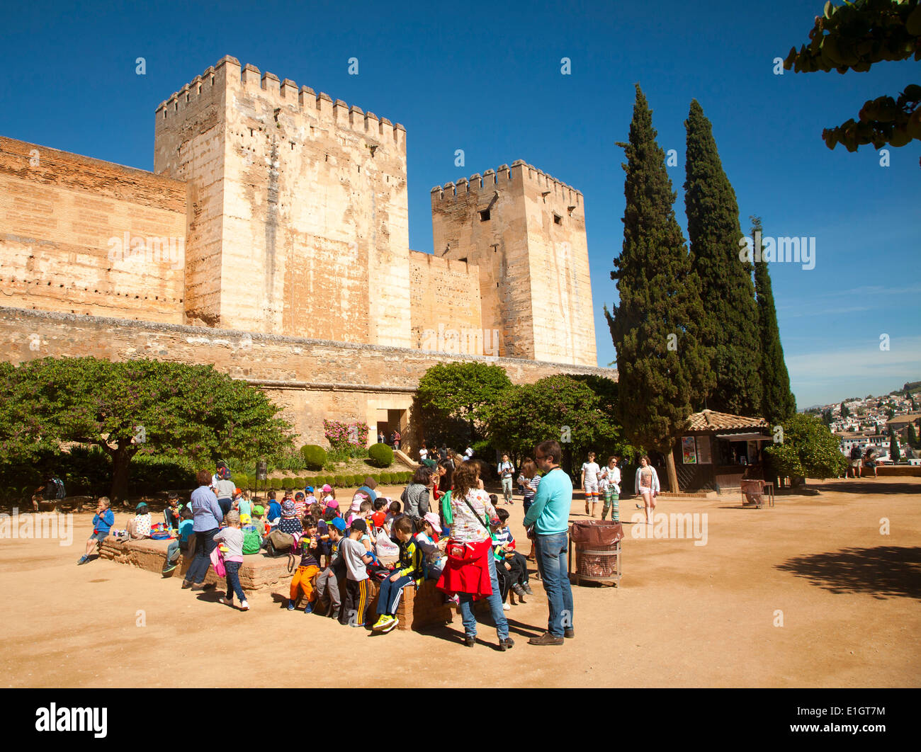 I bambini in gita scolastica seduto fuori il castello fortificato le pareti della storica Alcazaba, dell'Alhambra di Granada, Spagna Foto Stock