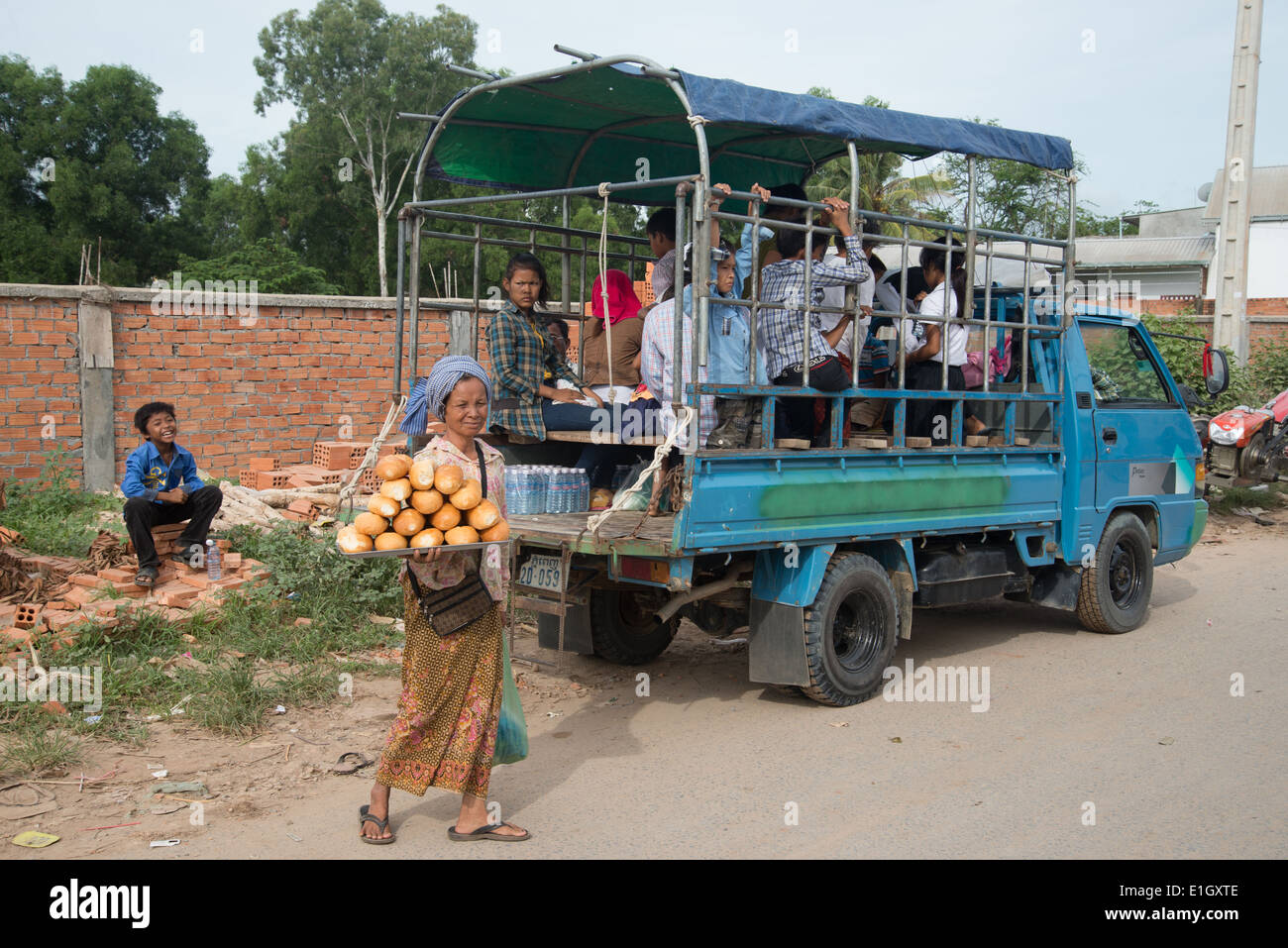 Camion autobus persone commutare, su biciclette su una strada polverosa, in Cambogia, camion, Foto Stock