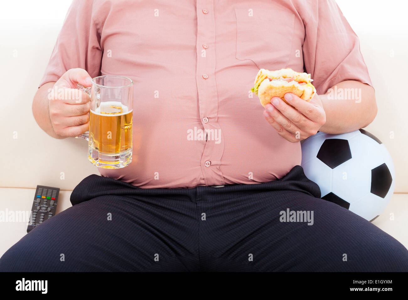 Fat business man a mangiare cibo e birra seduti sul divano Foto Stock
