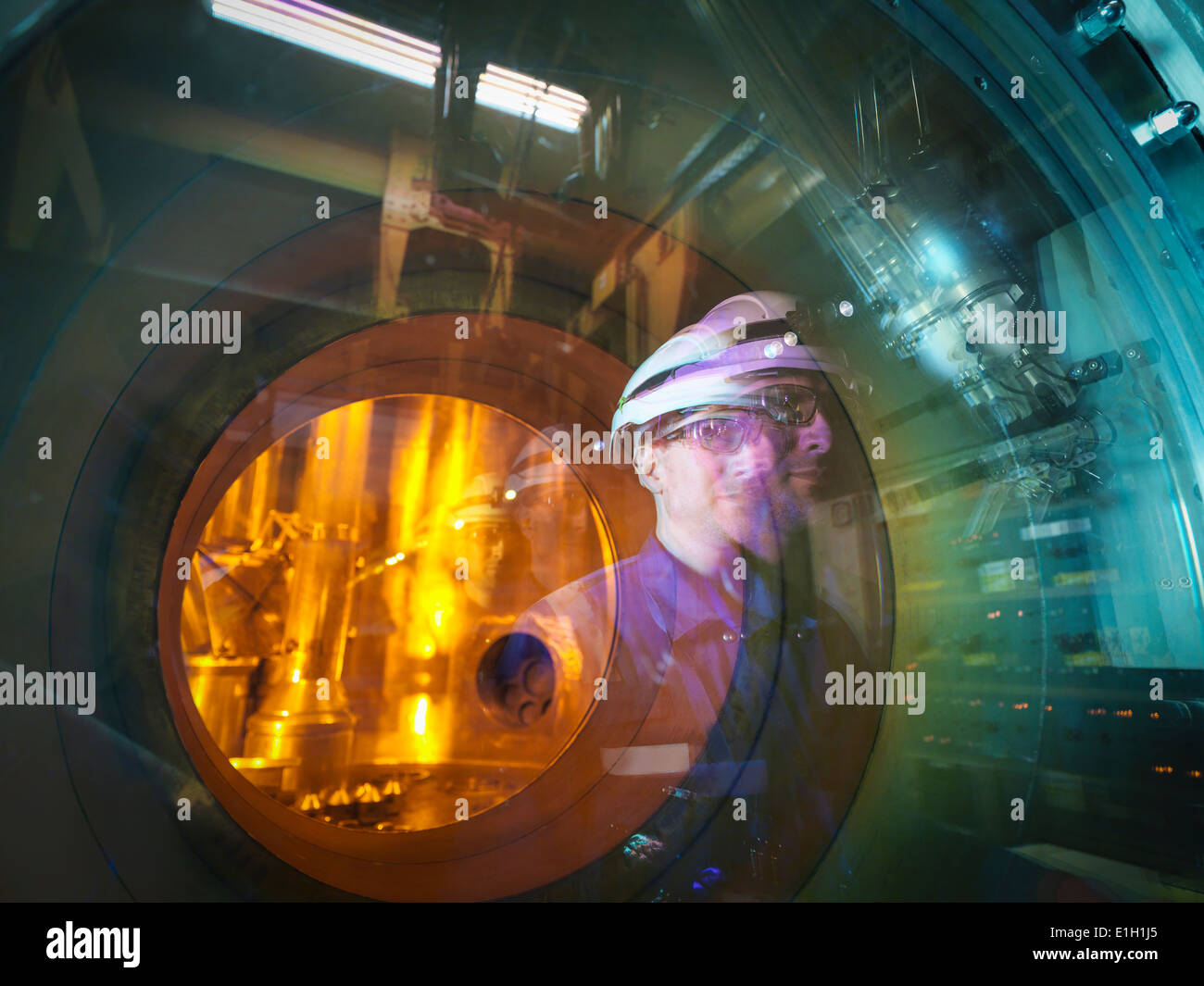 Ingegnere riflessa nel vetro di asta carburante macchina di movimentazione nella centrale nucleare Foto Stock
