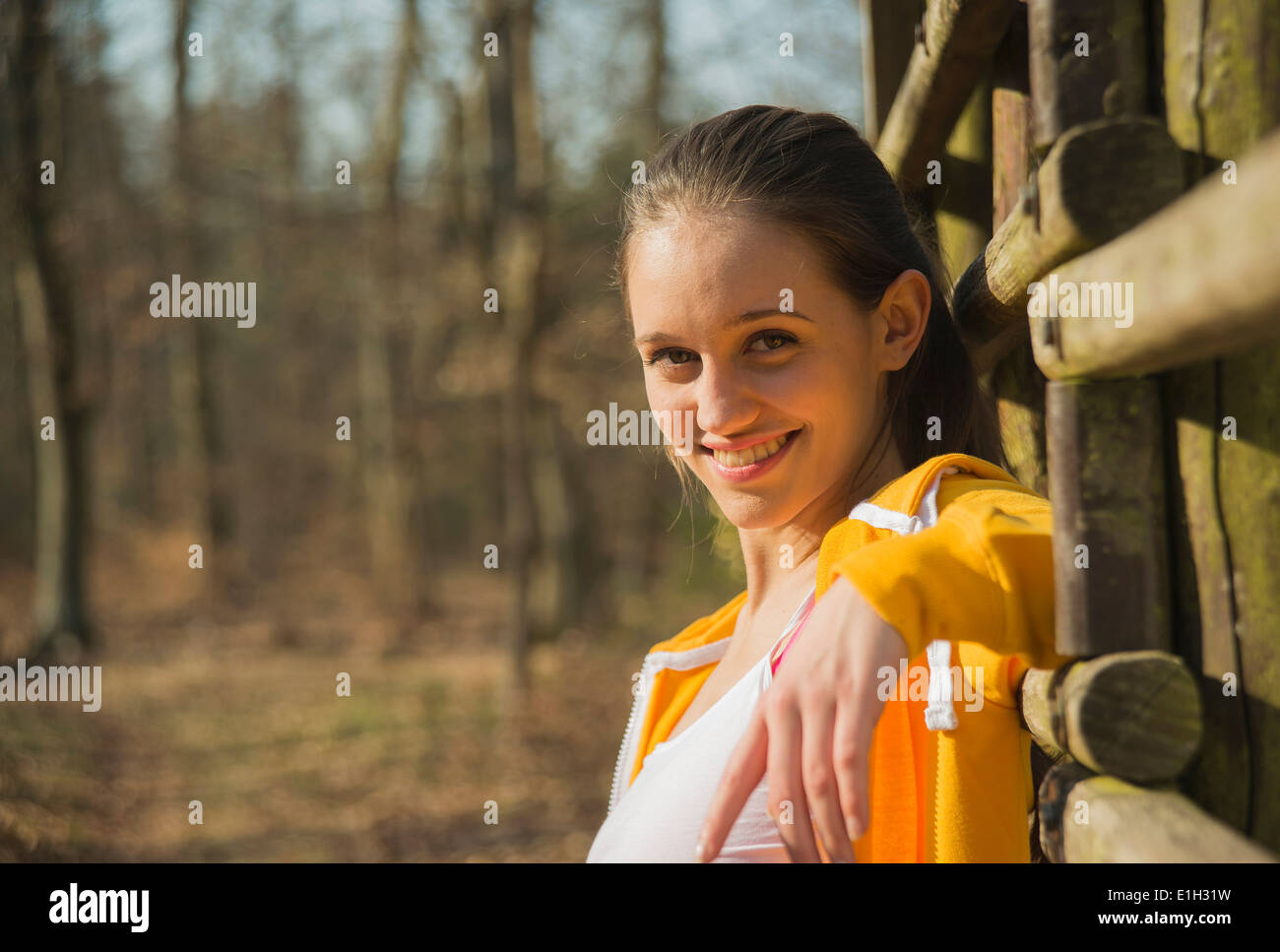Ritratto di giovane donna appoggiata contro la recinzione in foresta Foto Stock