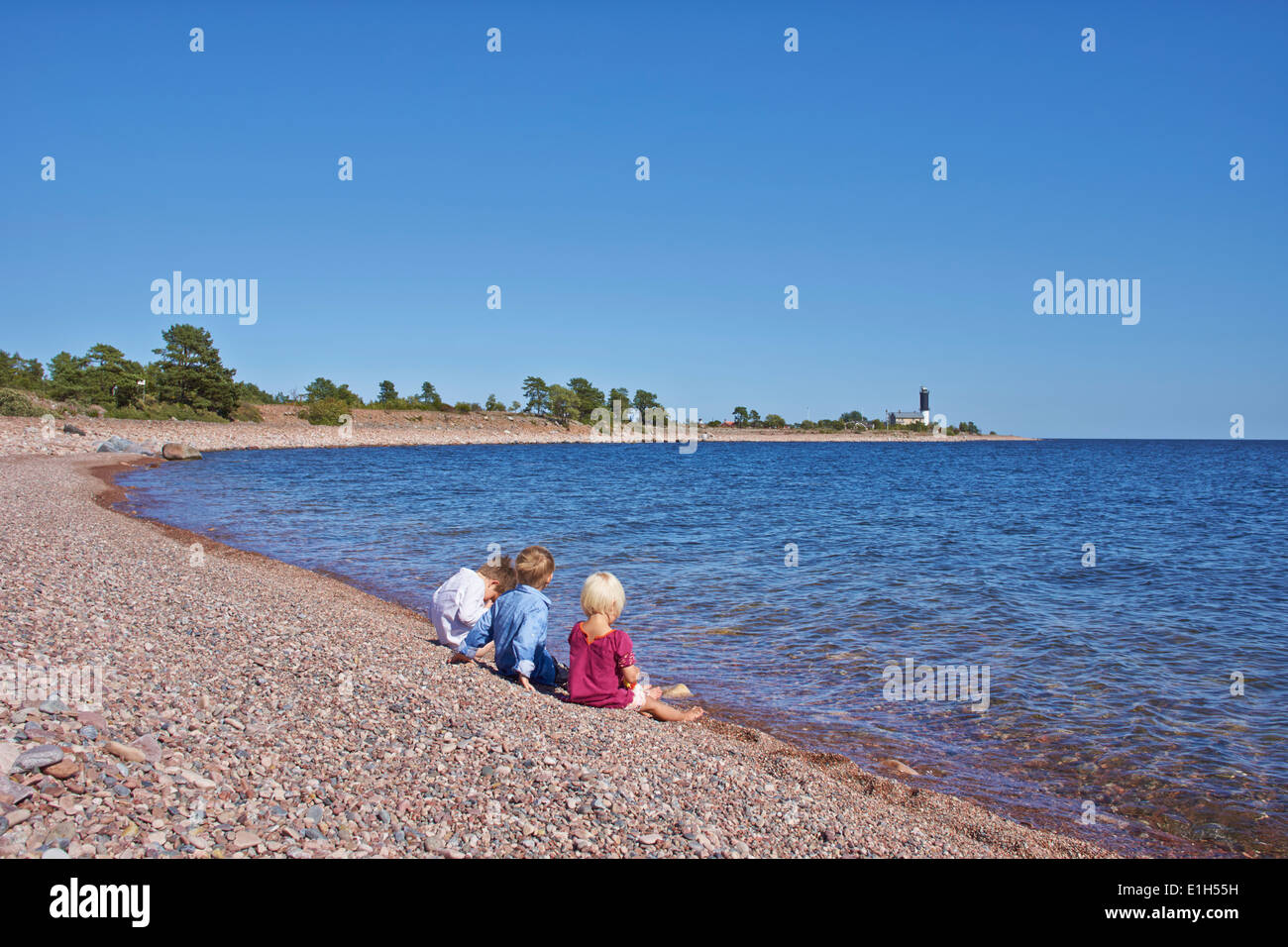 Tre bambini seduti sulla spiaggia Foto Stock