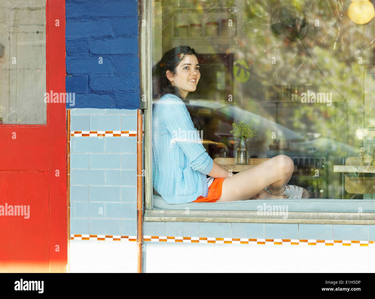 Giovane donna guardando fuori della finestra cafe Foto Stock