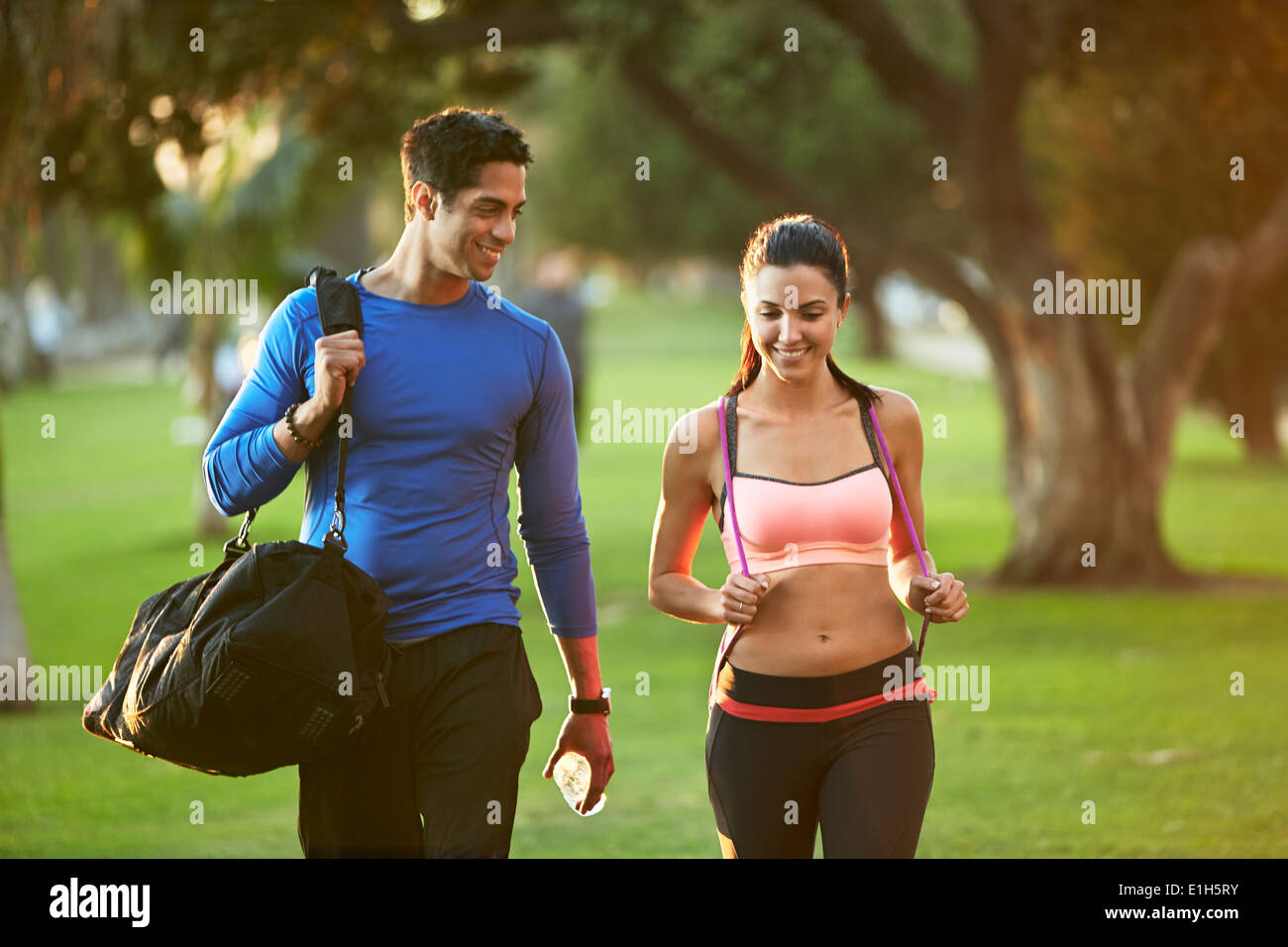 Uomo e donna che indossa abbigliamento sportivo a piedi attraverso il parco Foto Stock