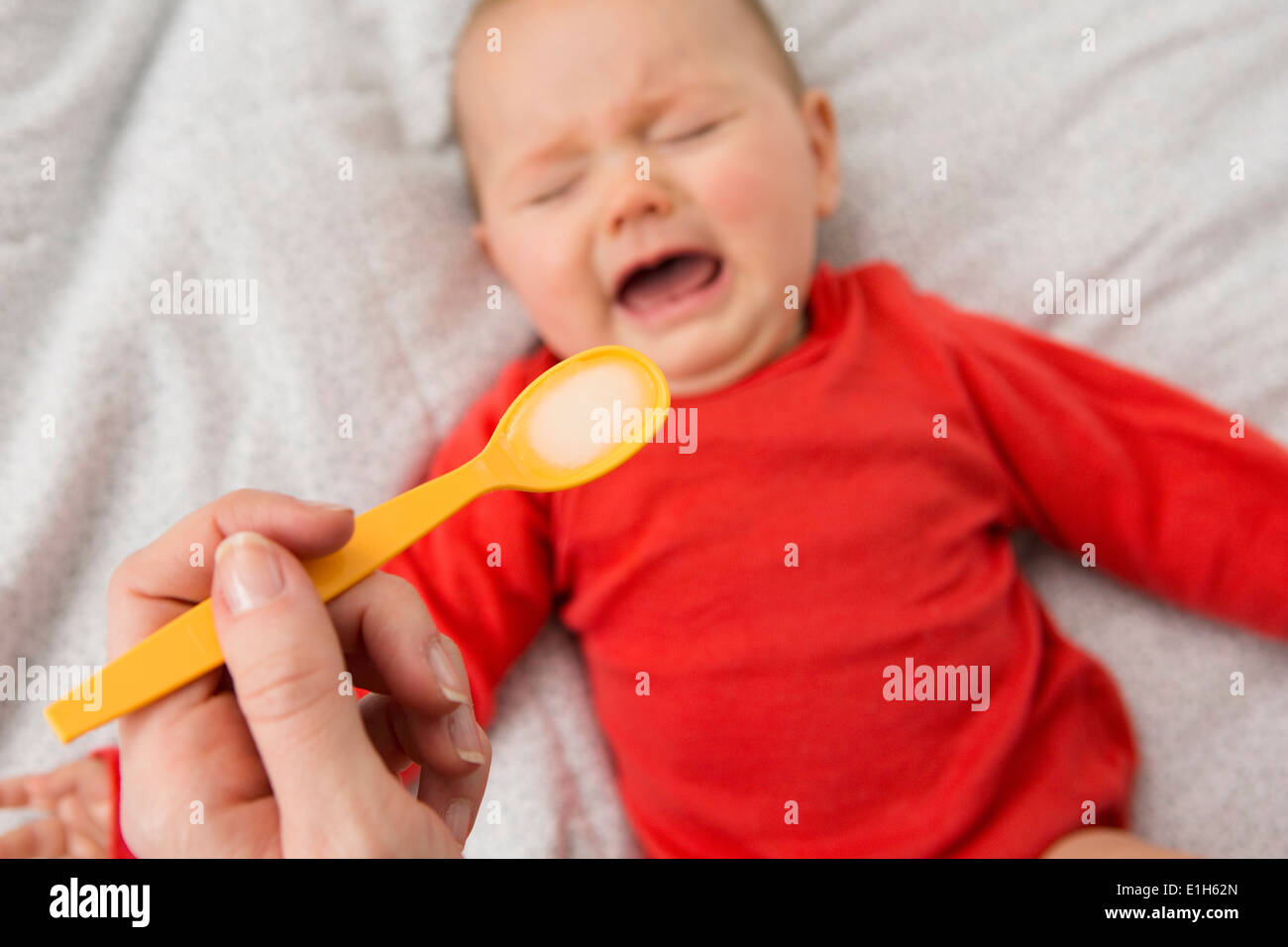 Le madri mano azienda cucchiaio per alimentare Gridando bambino figlia Foto Stock
