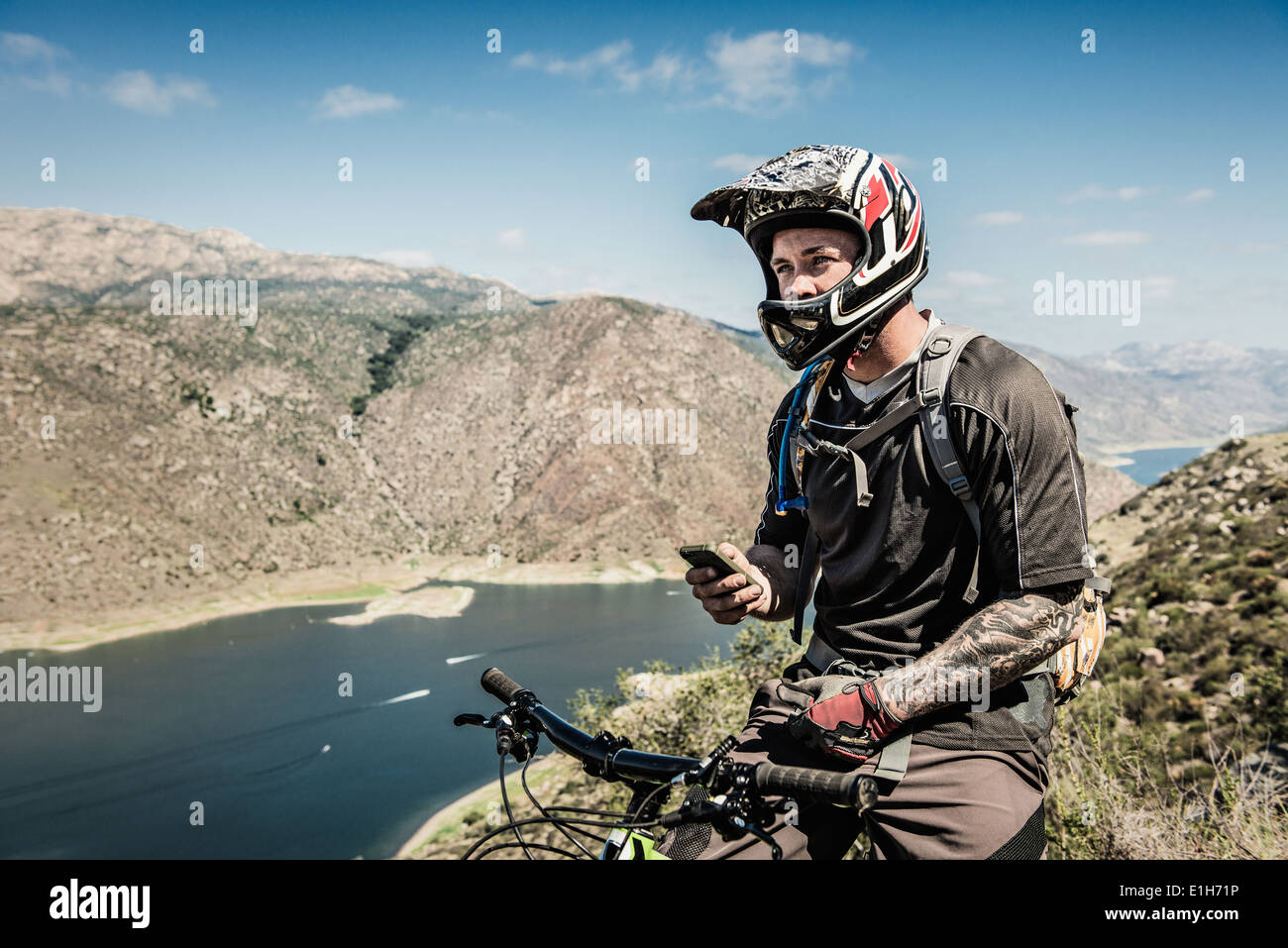 Downhill mountain biker utilizza lo smartphone Foto Stock
