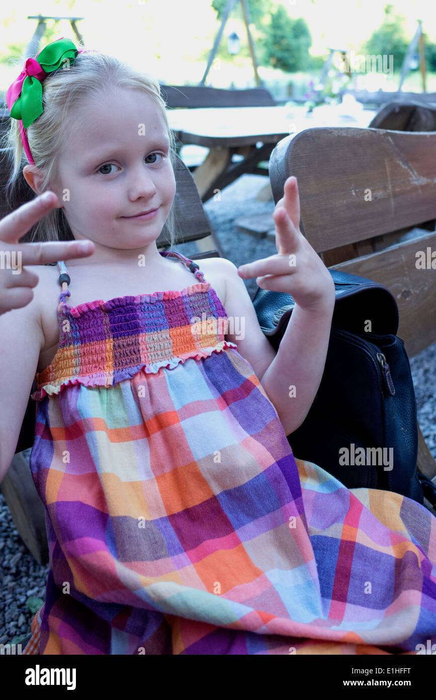 Ragazza 6 anni indossando un madras plaid dress dando un segno in attesa per la cena in un ristorante all'aperto. Spala Polonia centrale Foto Stock