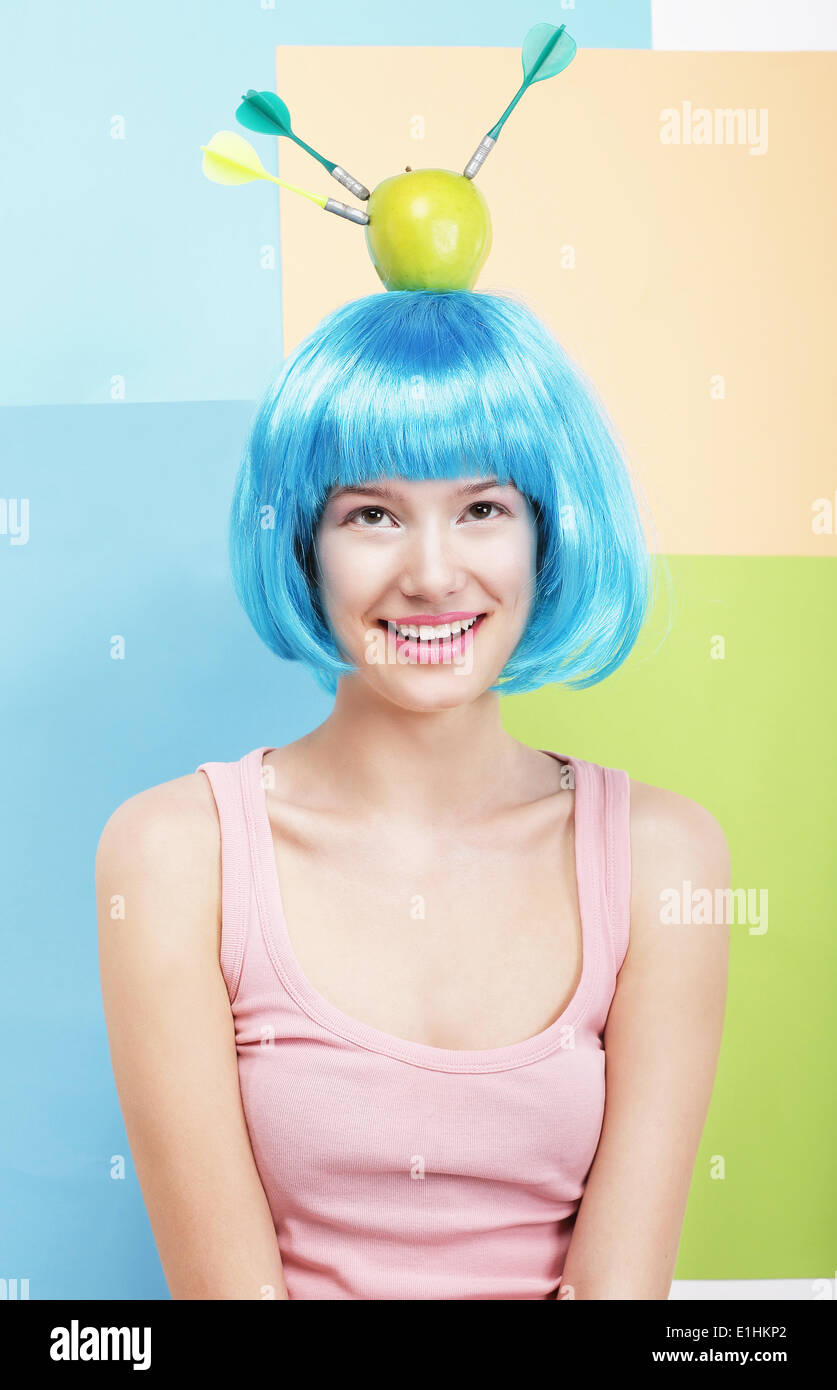 Precisione. Divertenti donna in Parrucca Blu, Verde mela e freccette Foto Stock