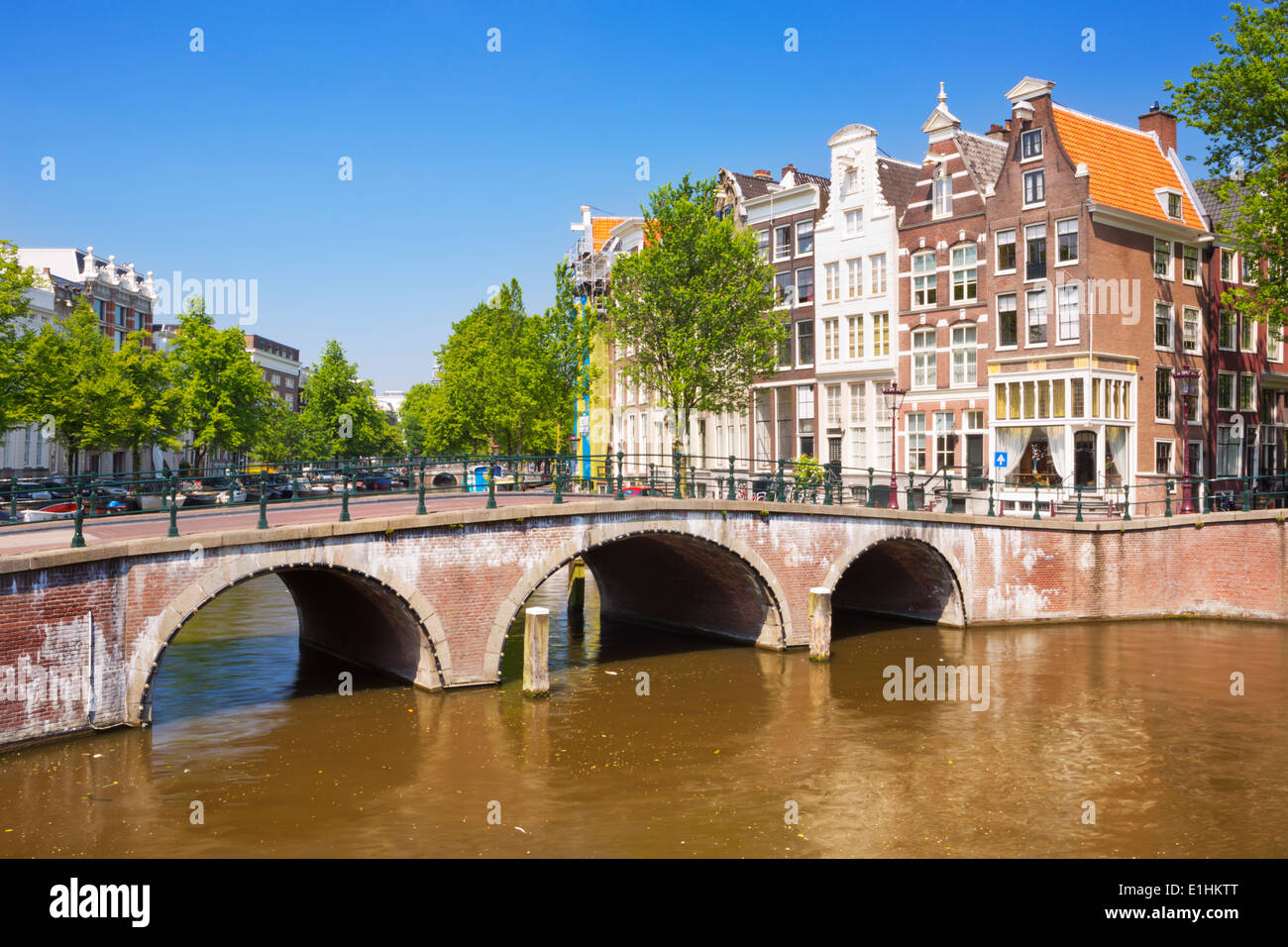 Ponti e case lungo un canale nella città di Amsterdam e i Paesi Bassi in una bella giornata di sole Foto Stock