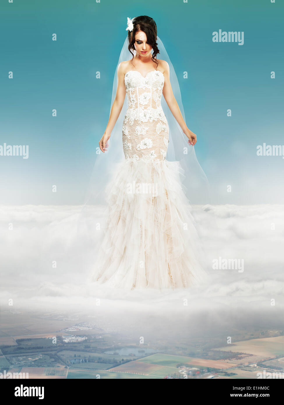 Sposa matrimonio abito bianco in piedi su una nuvola e guardando a terra Foto Stock