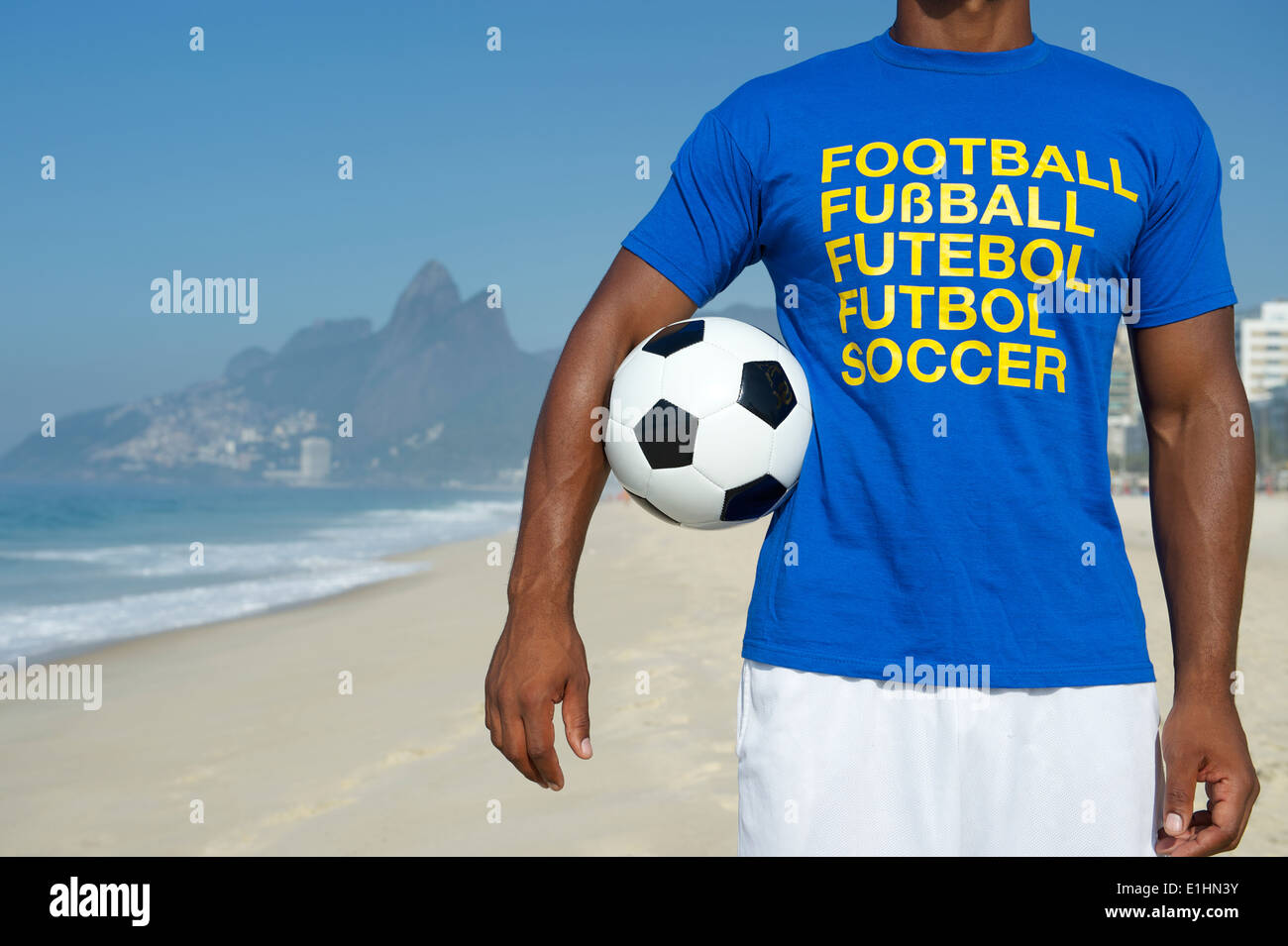 Il calcio brasiliano player in multi lingua messaggio t-shirt tenendo palla calcio la spiaggia di Ipanema di Rio de Janeiro in Brasile Foto Stock
