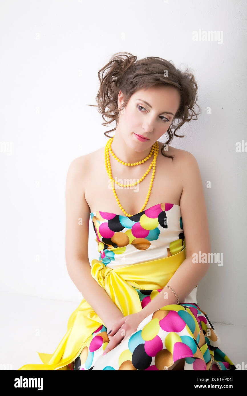 Bene Ritratto di giovane bella ragazza triste in un colorito luminoso abito. Studio shot Foto Stock