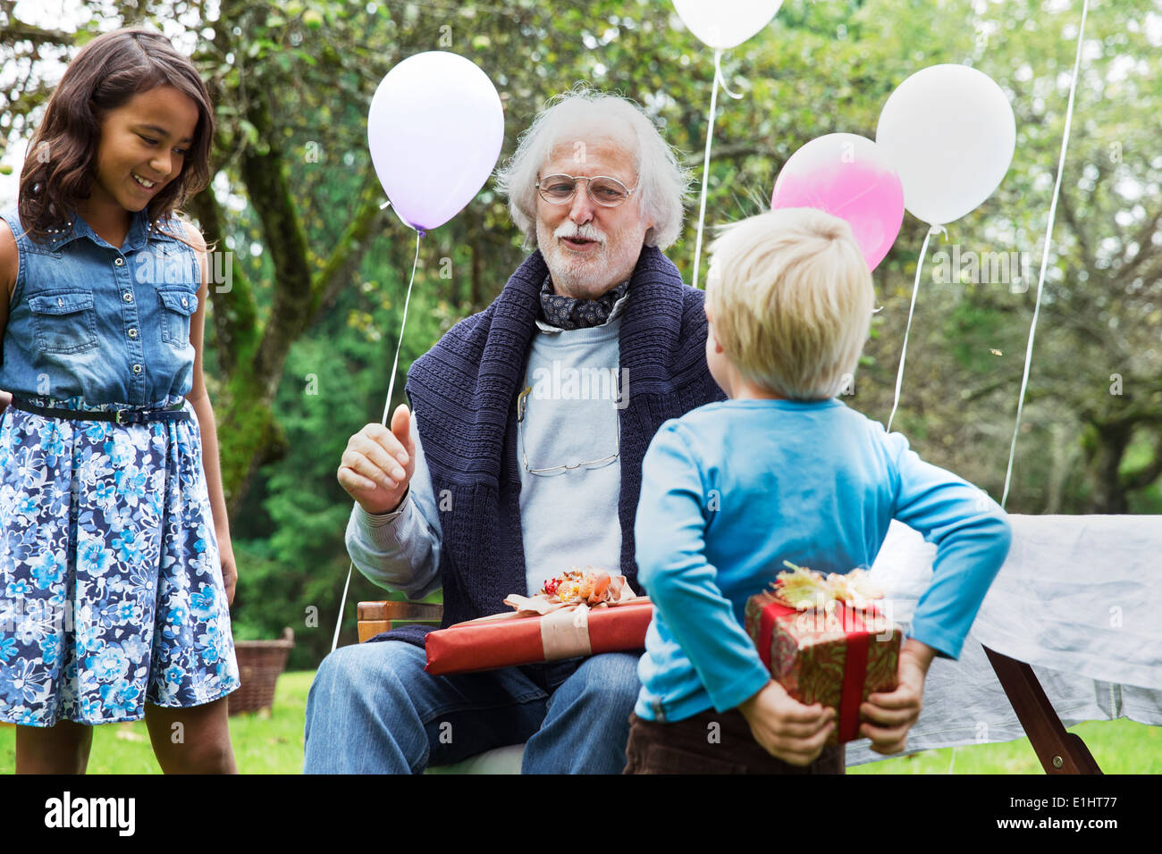 Nonno ricevere doni sulla festa di compleanno in giardino Foto Stock