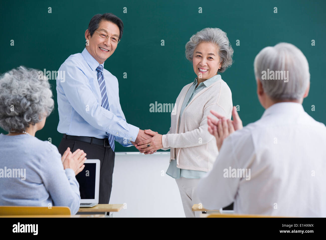 Anziano studente avente un handshake con insegnante in classe Foto Stock