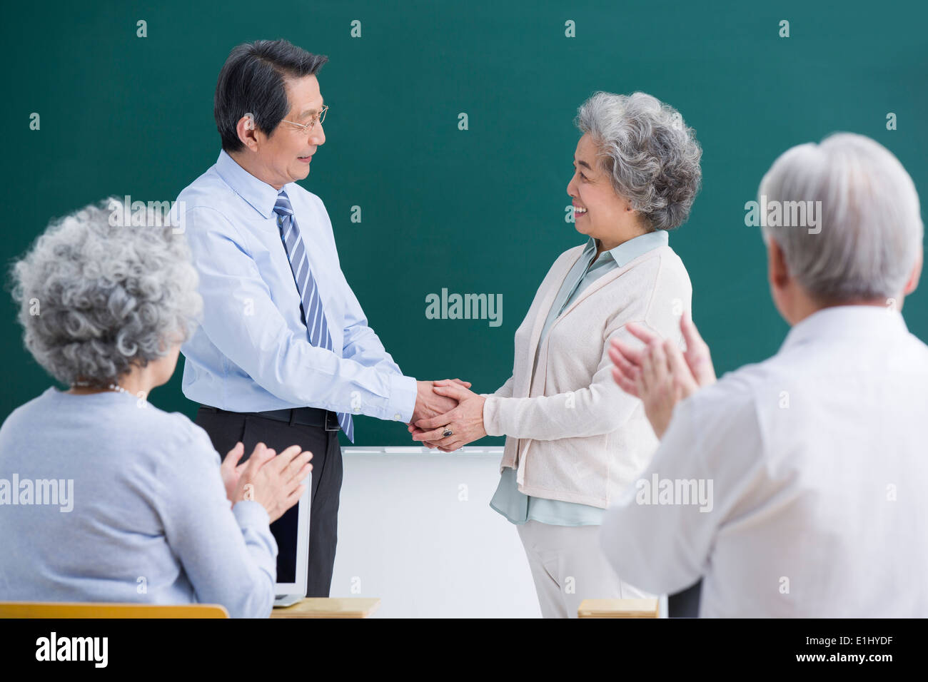 Anziano studente avente un handshake con insegnante in classe Foto Stock