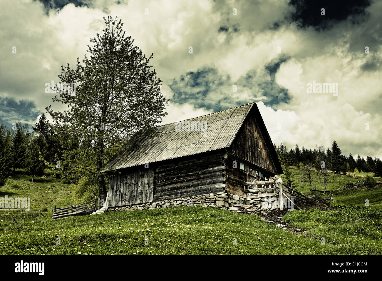 Drammatico paesaggio con un vecchio fienile su un prato e moody sky Foto Stock