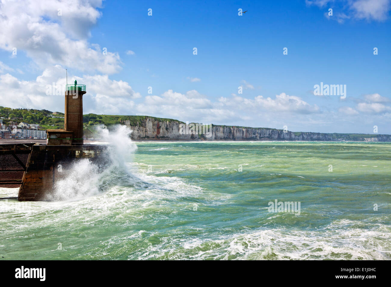 Onde che si infrangono al faro verde del porto di entrata a Fecamp, Normandia, Francia. Le scogliere della costa di alabastro in background. Foto Stock