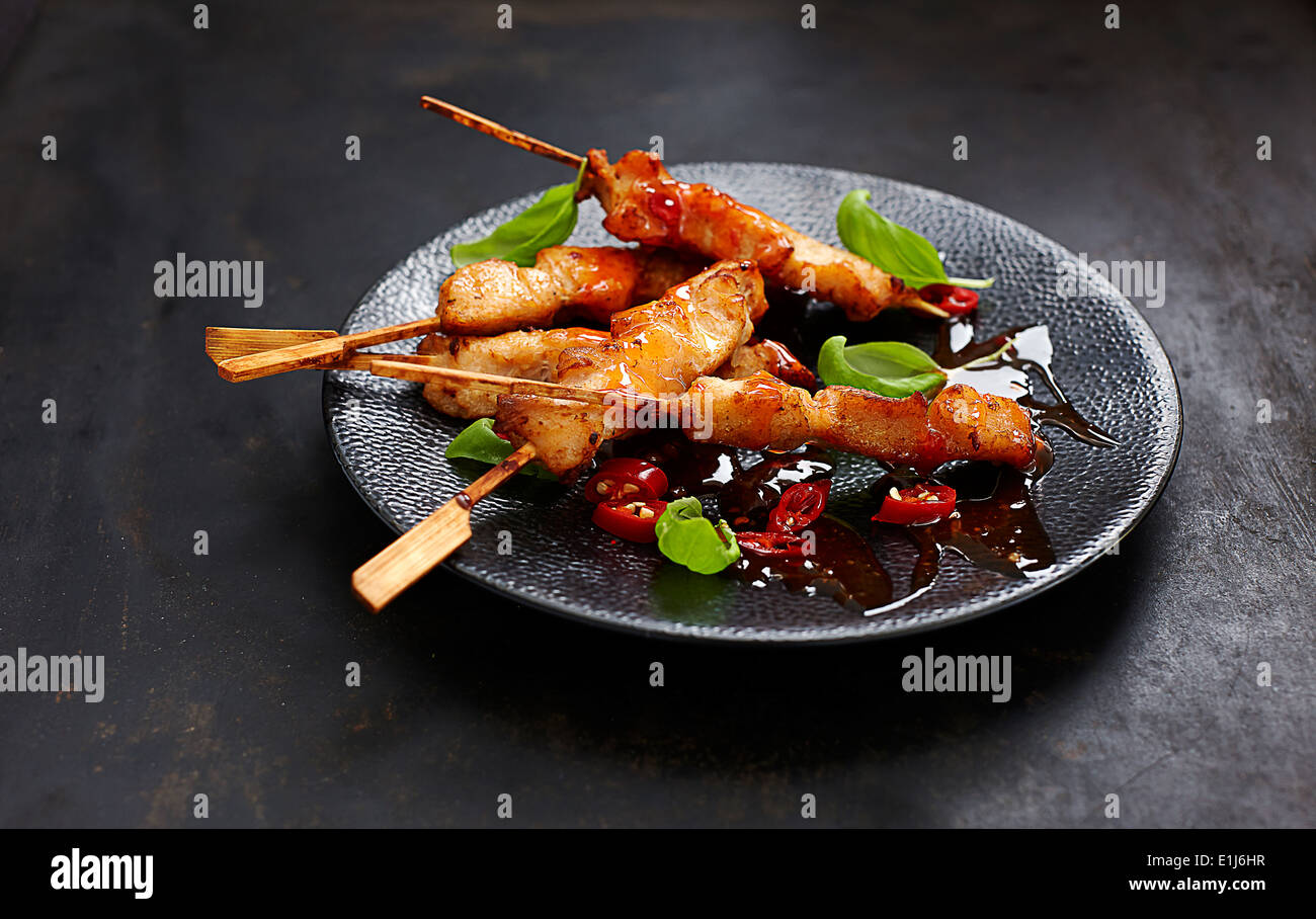 Spiedini di pollo con agrodolci e salsa di peperoncino su piastra Foto Stock