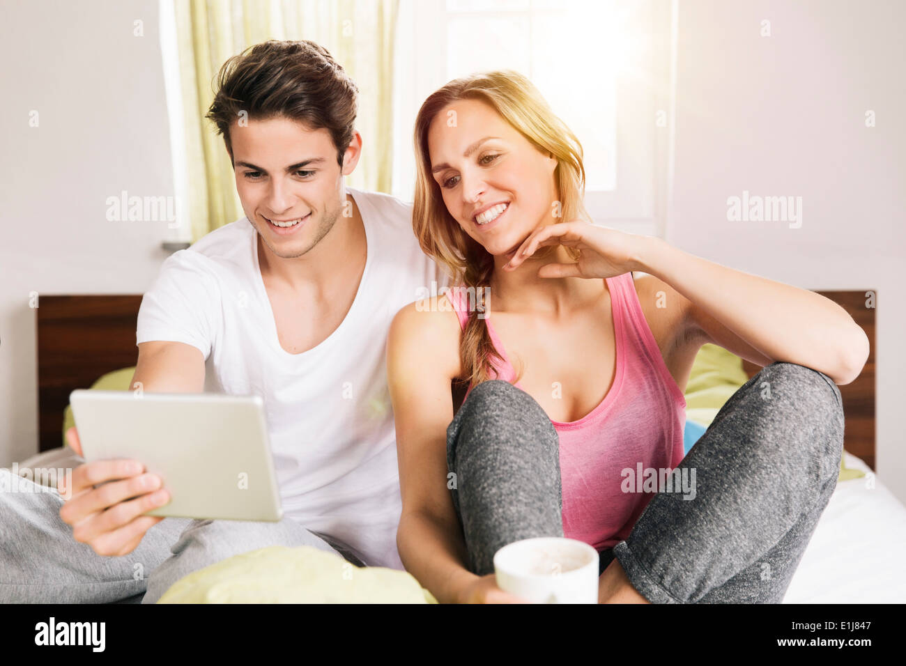 Coppia giovane guardando un computer tablet mentre è seduto sul letto Foto Stock
