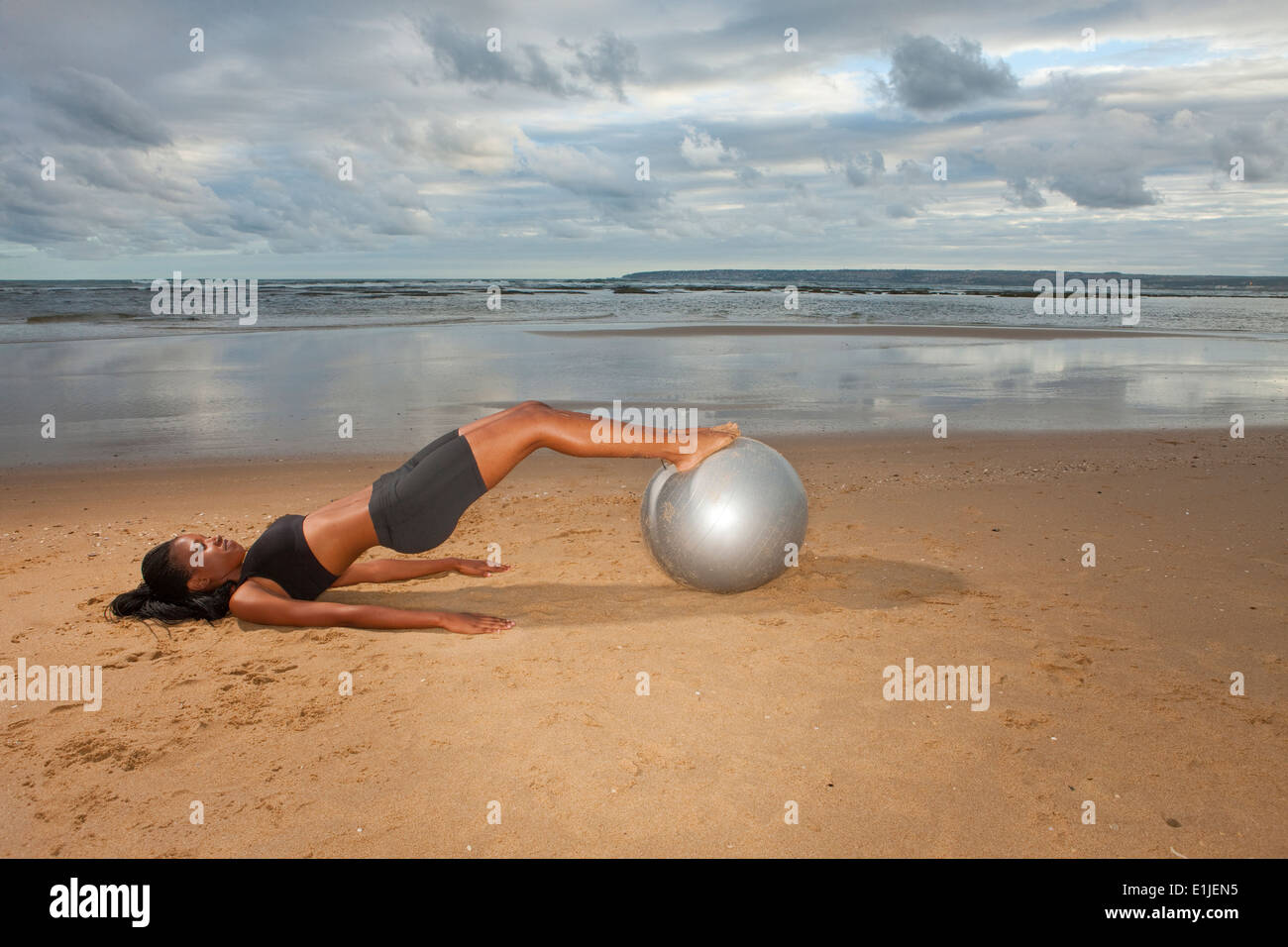 Giovane donna pratica dello yoga con palla ginnica presso la spiaggia Foto Stock