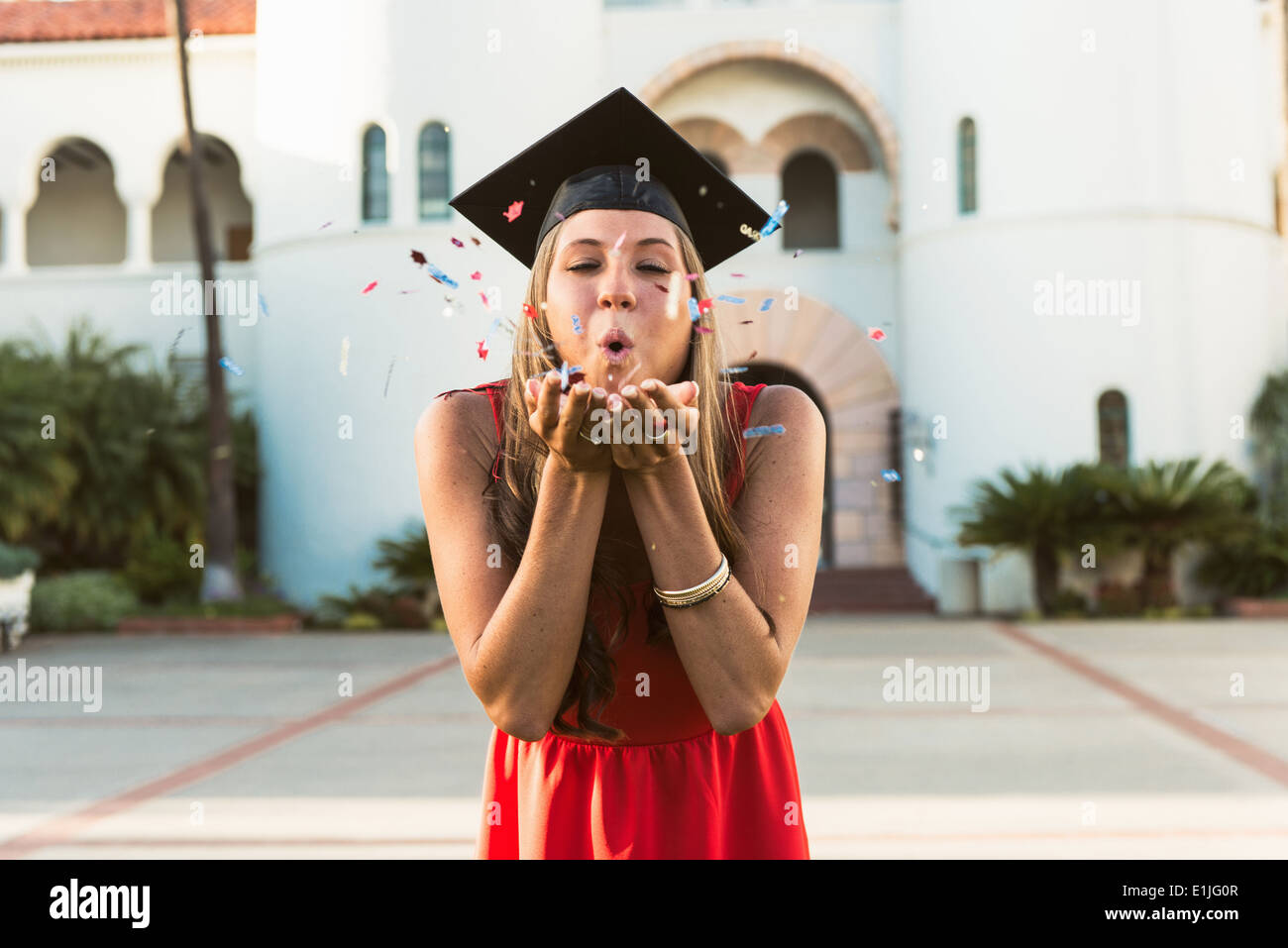 Laureato femmina soffiando confetti di mani Foto Stock