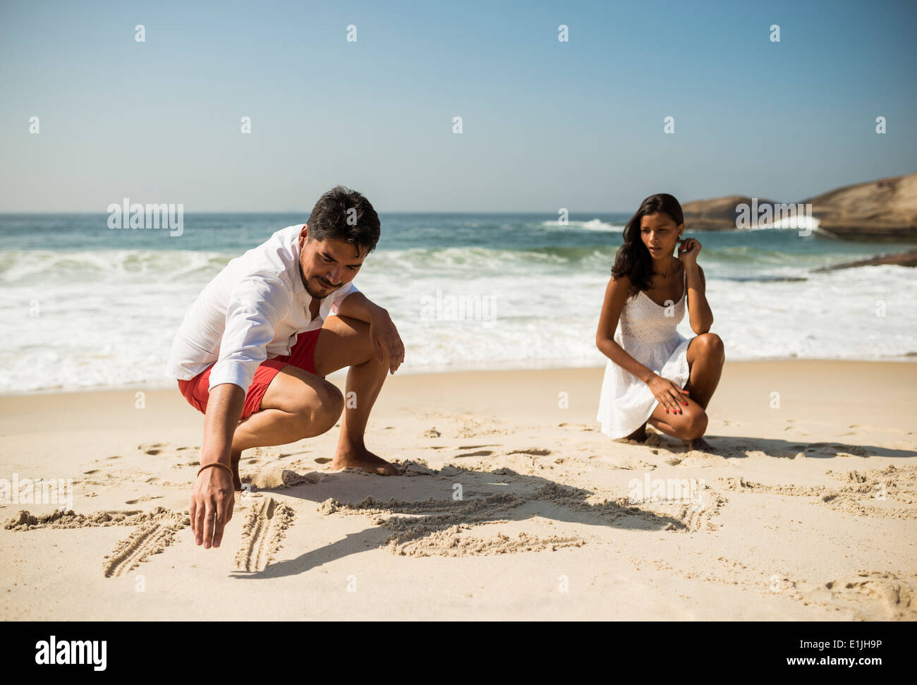 Giovane iscritto nella sabbia sulla spiaggia di Arpoador, Rio de Janeiro, Brasile Foto Stock