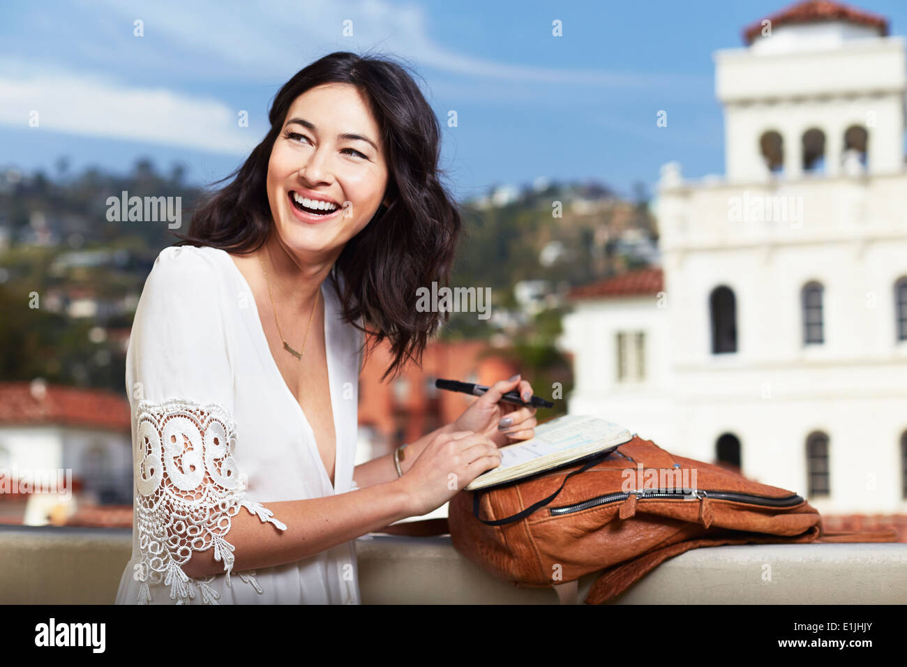 Giovane donna iscritto in notebook all'aperto Foto Stock